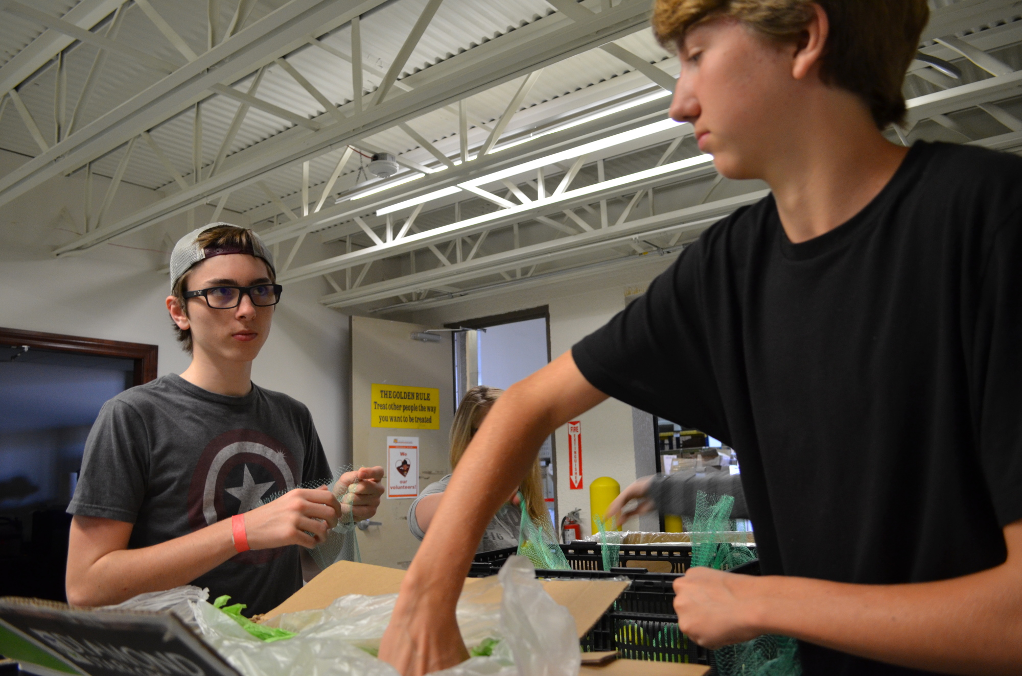 MacKenzie Vance and Forrest St. Pierre help package pears at All Faiths Food Bank during spring break.