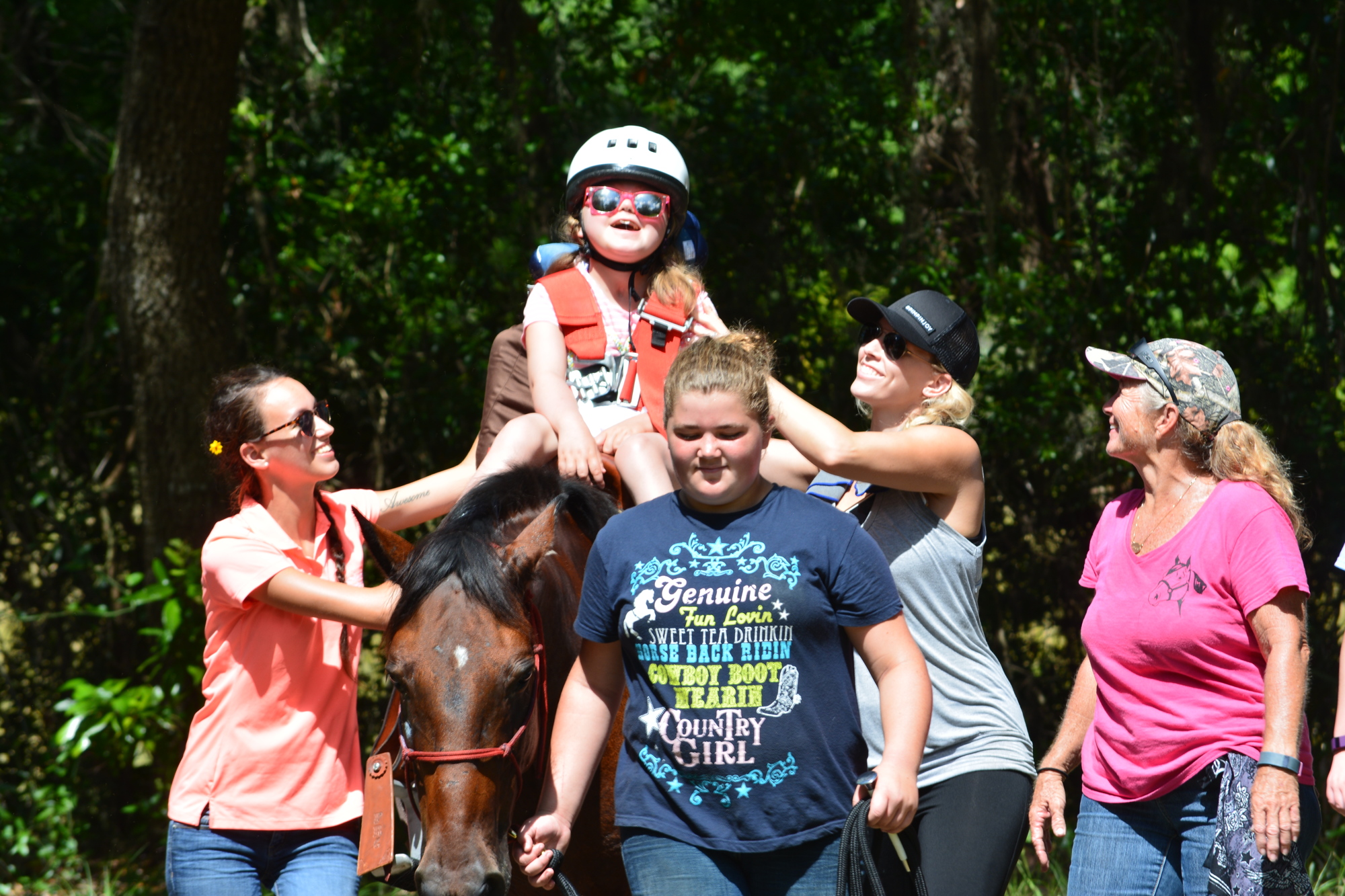 Taylor Holweger rides a horse for the first time with the support of Regina Holder, Maddy Hartwig, Jeana Miller and Kathy Wolfe.