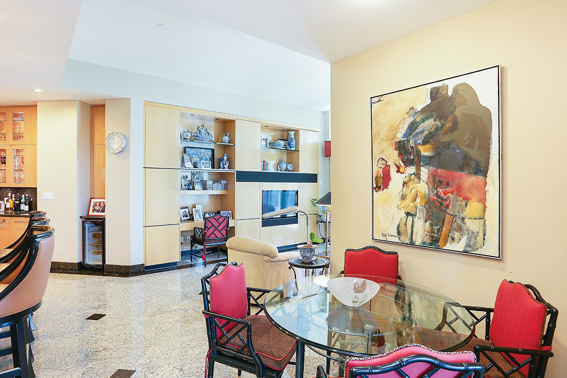 One of two identical tables in the dining room. The painting is by Syd Solomon, whose work is on display throughout the apartment. In the distance, a glimpse into the family room.