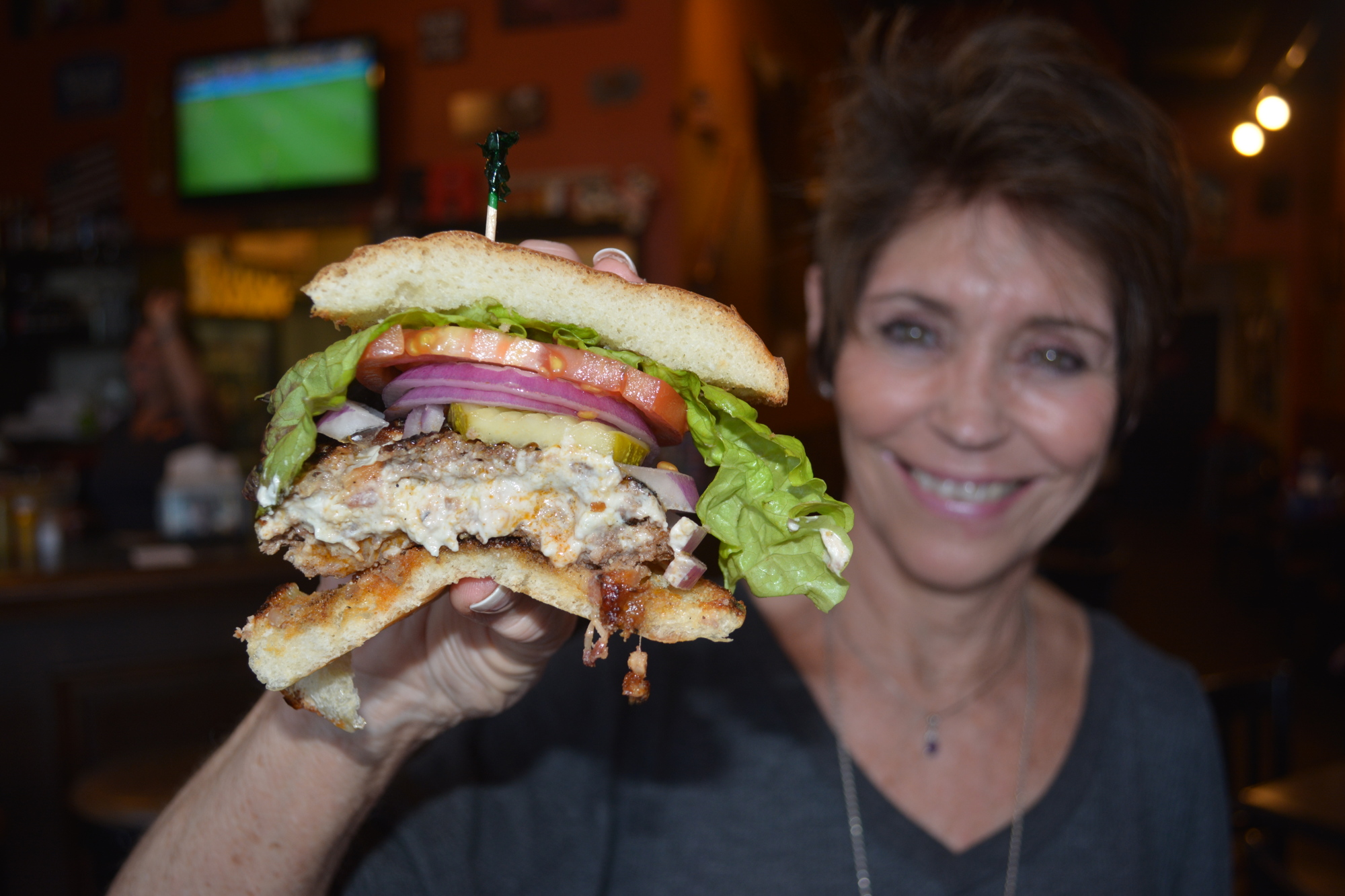 Pinki Goolsby shows off a Cheddar Bacon burger from Full Belly Stuffed Burgers.