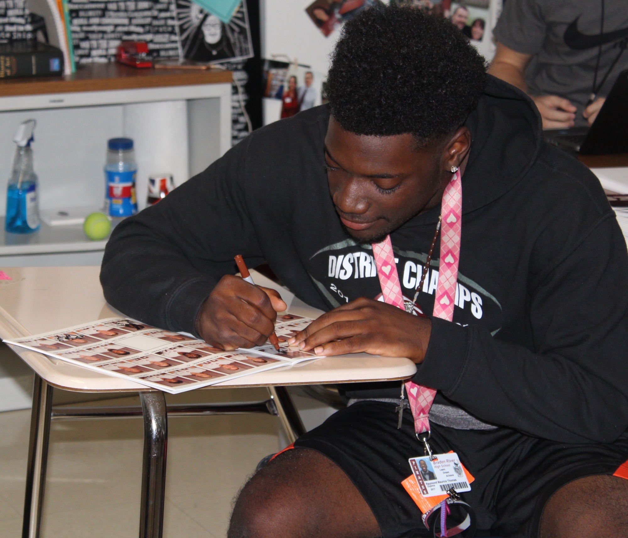 Senior Raymond Thomas signs a sports program for the Homecoming for Heroes care package.