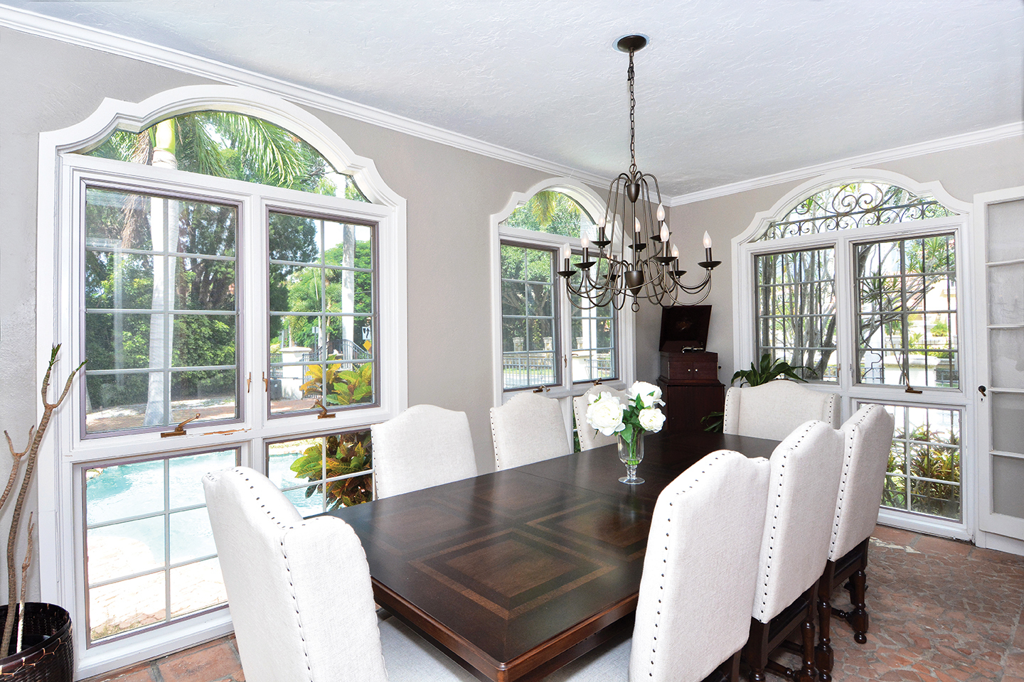 In the dining room, graceful windows overlook the paver patio. The floors are an unusual treatment of broken brick.