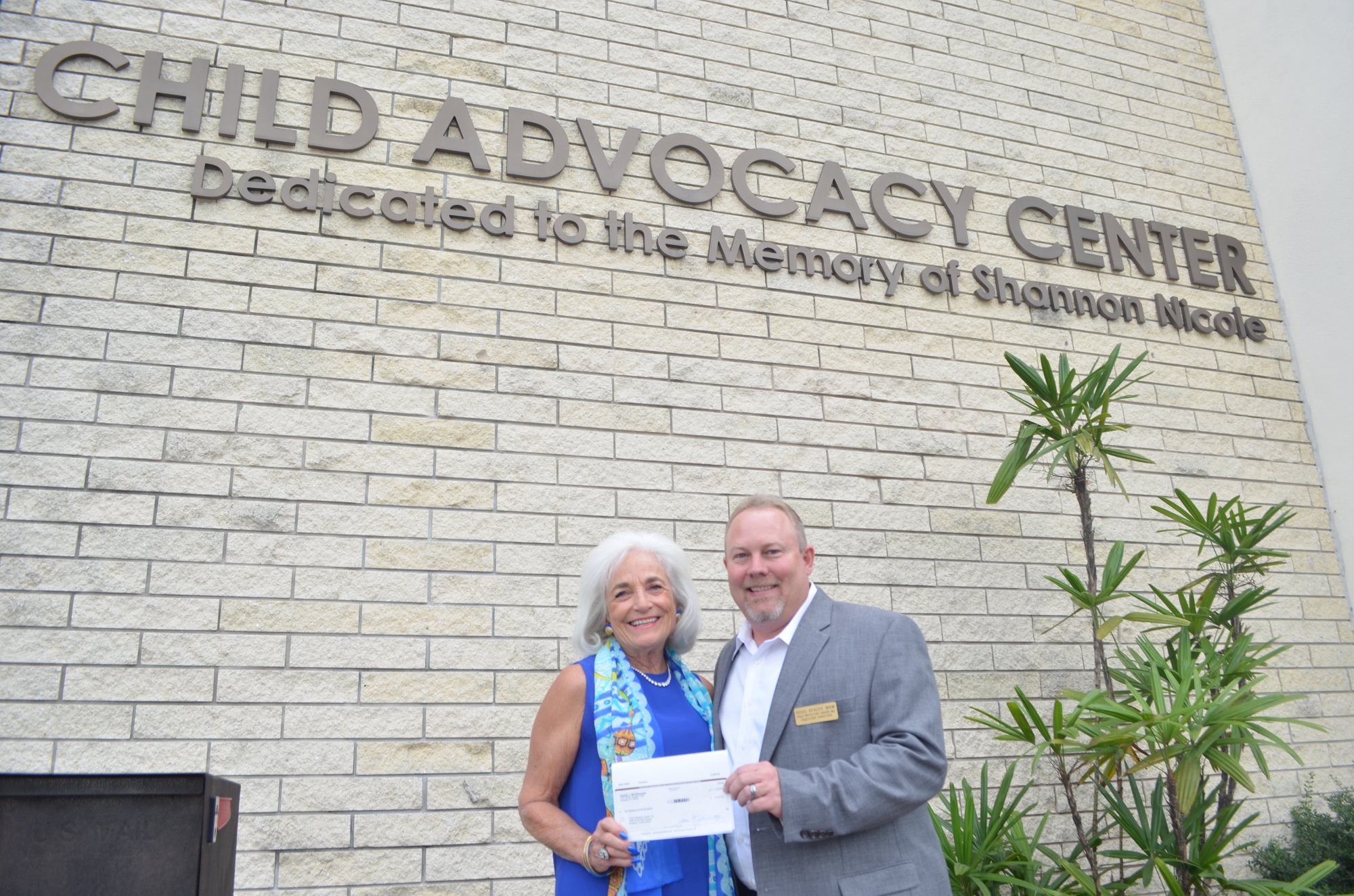 Graci McGillicuddy presents Douglas S. Staley, CEO of Child Protection Center, with her birthday donation check. Photo by Niki Kottmann.