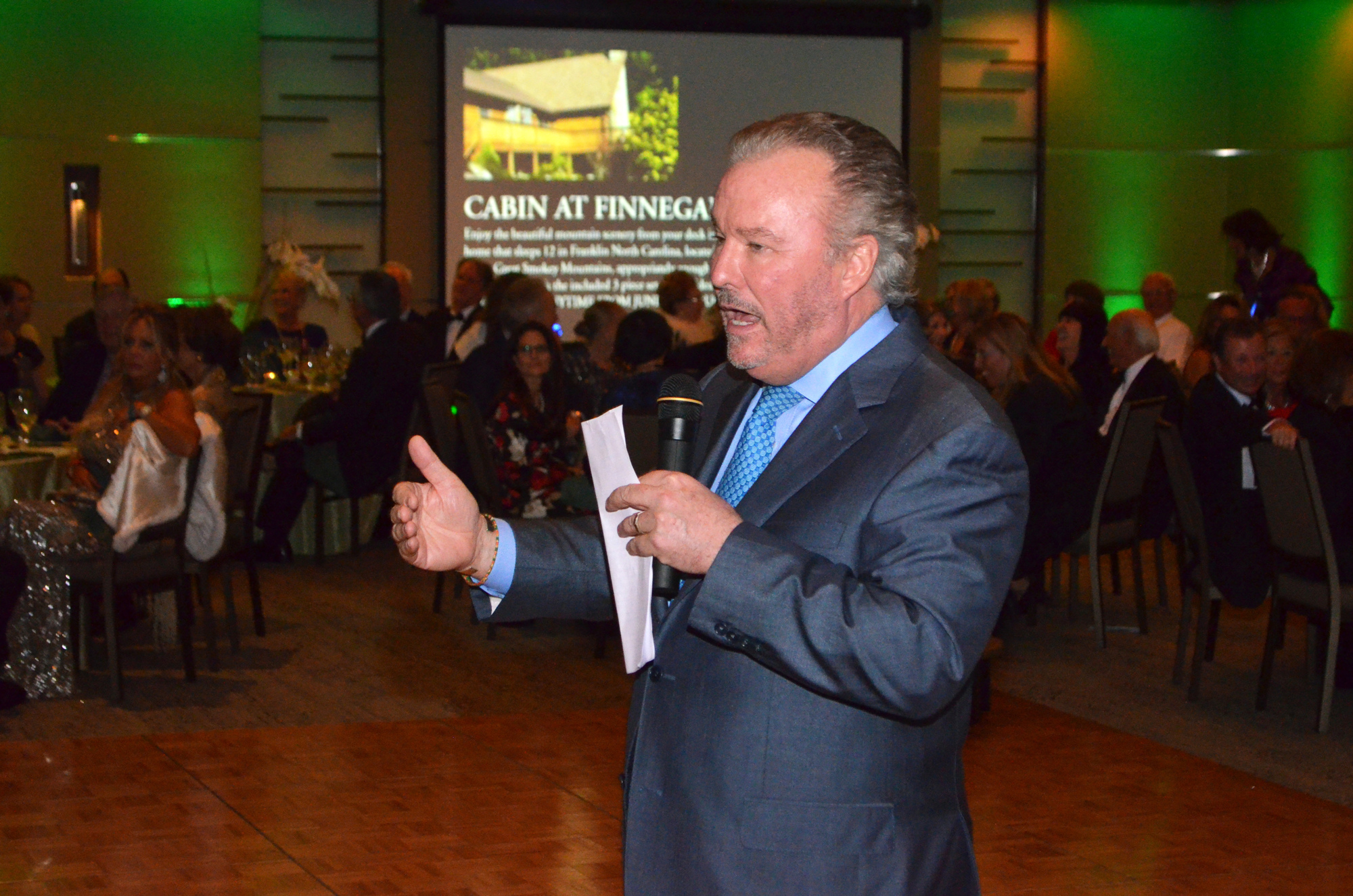 Michael Klauber encourages attendees to bid on the Cabin at Finnegan's Barn auction item. Photo by Niki Kottmann