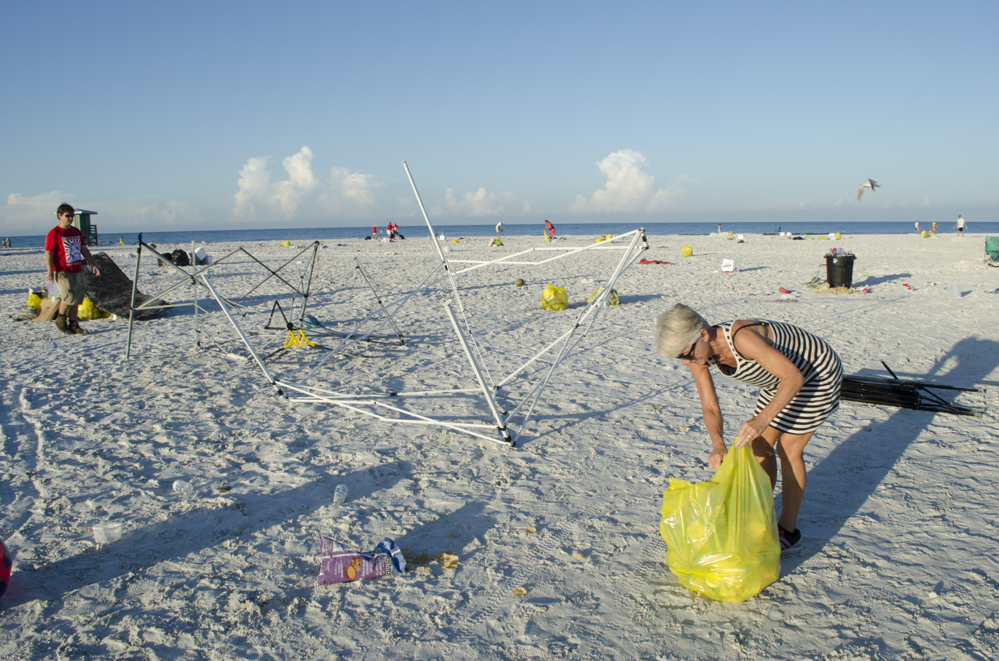 Kris Tikson picks up trash on Siesta Beach near an abandoned tent frame. She felt compelled to help with the cleanup efforts after she saw the Memorial Day mess.
