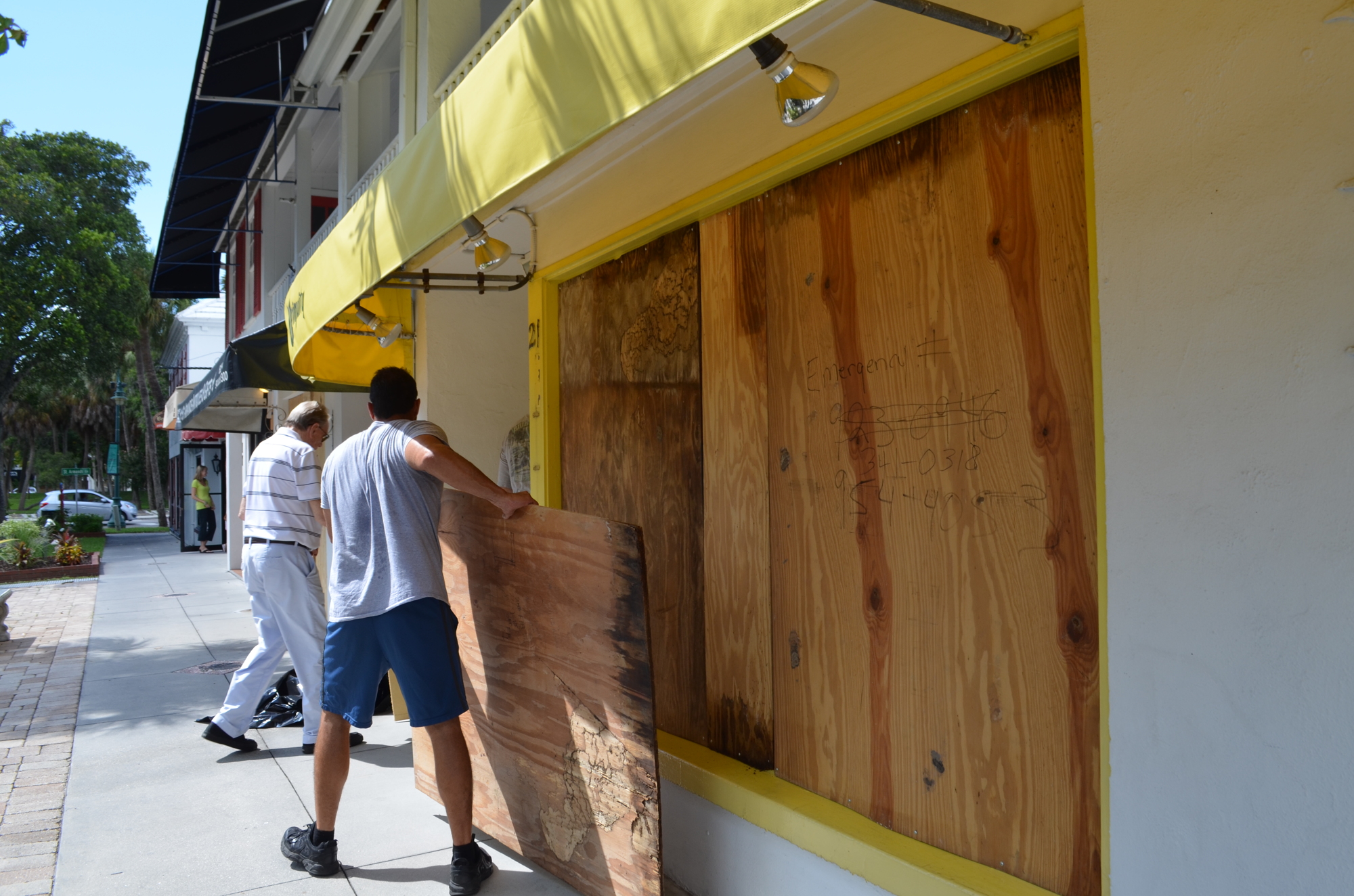 Workers board up the windows at Uniquity on St. Armands Circle on Friday.