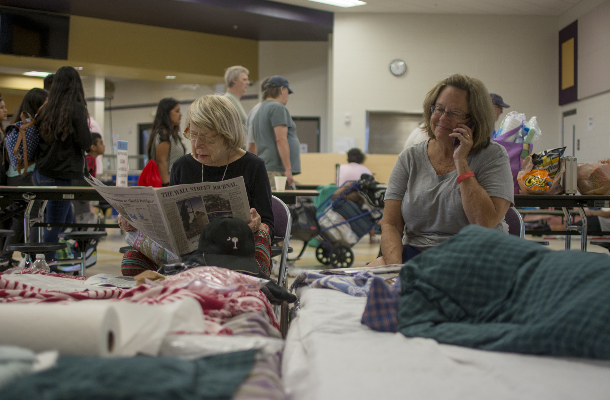  Larissa Green reads the Wall Street Journal while her daughter Ann Green West talks on the phone at Booker High School on Saturday. The pair arrived with Howard Green on Friday night. 