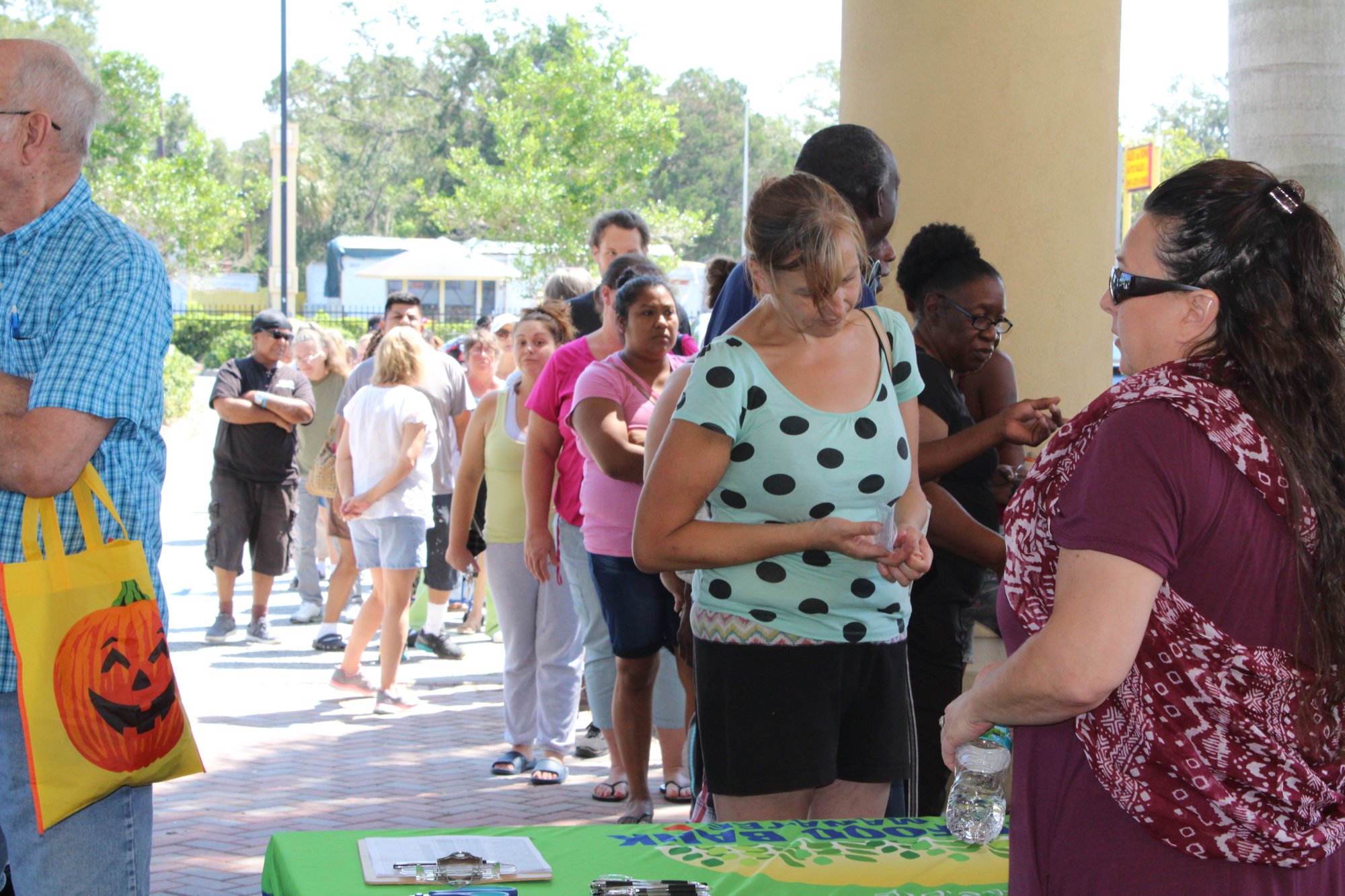Manatee County residents wait in line for free water and food provided by The Food Bank of Manatee.