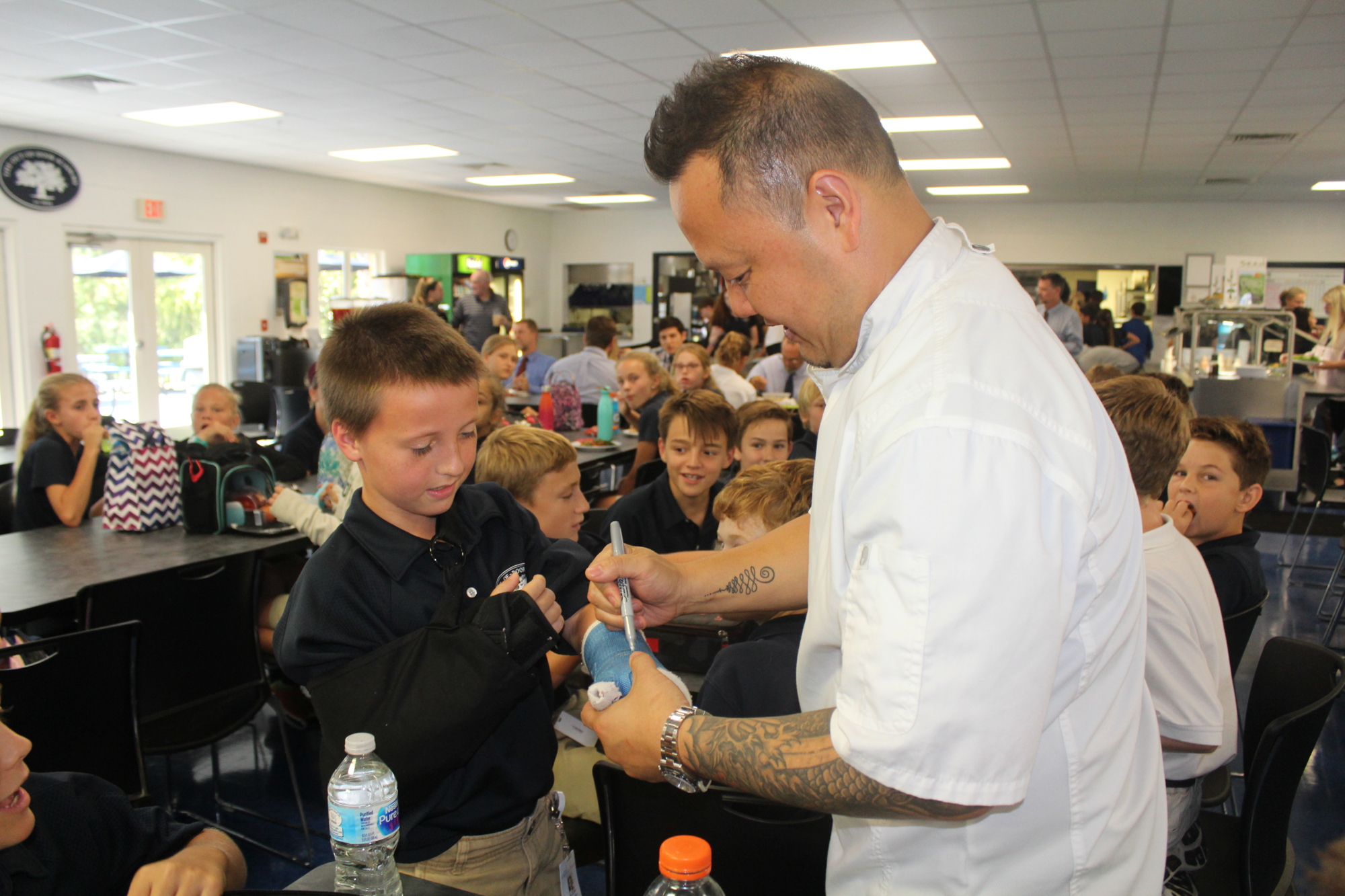 Out-of-Door Academy sixth-grader Alex Ross asks Chef Jet Tila to sign his cast.
