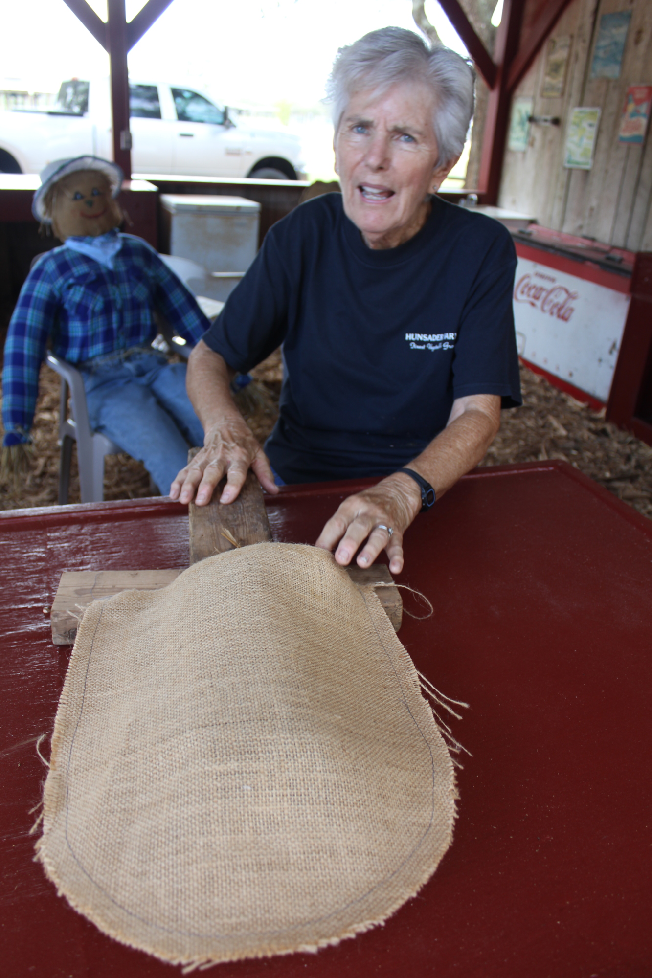 Connie Hunsader demonstrates how to cut the burlap that eventually will have a face painted on it, before being sewn together, stuffed and then nailed to a base.