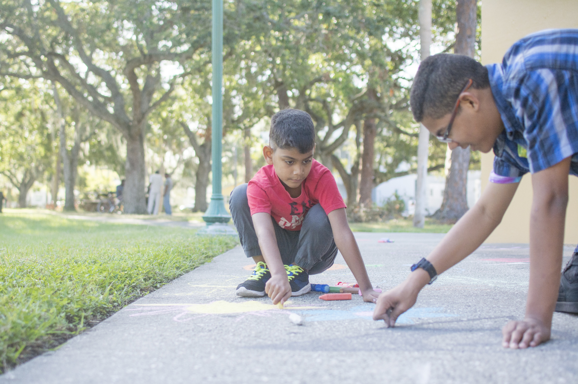 Damian Rosario draws on the side walk near the Gillespie Park pavilion during the neighborhood's celebration of its new butterfly garden.