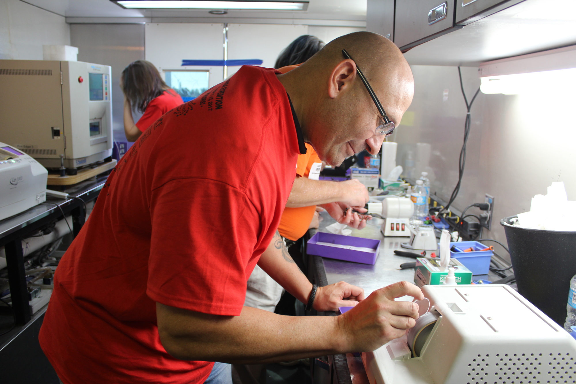 Dennis Kleban, a licensed optician, smooths the edges of a prescription, one of many steps in the production process for glasses.