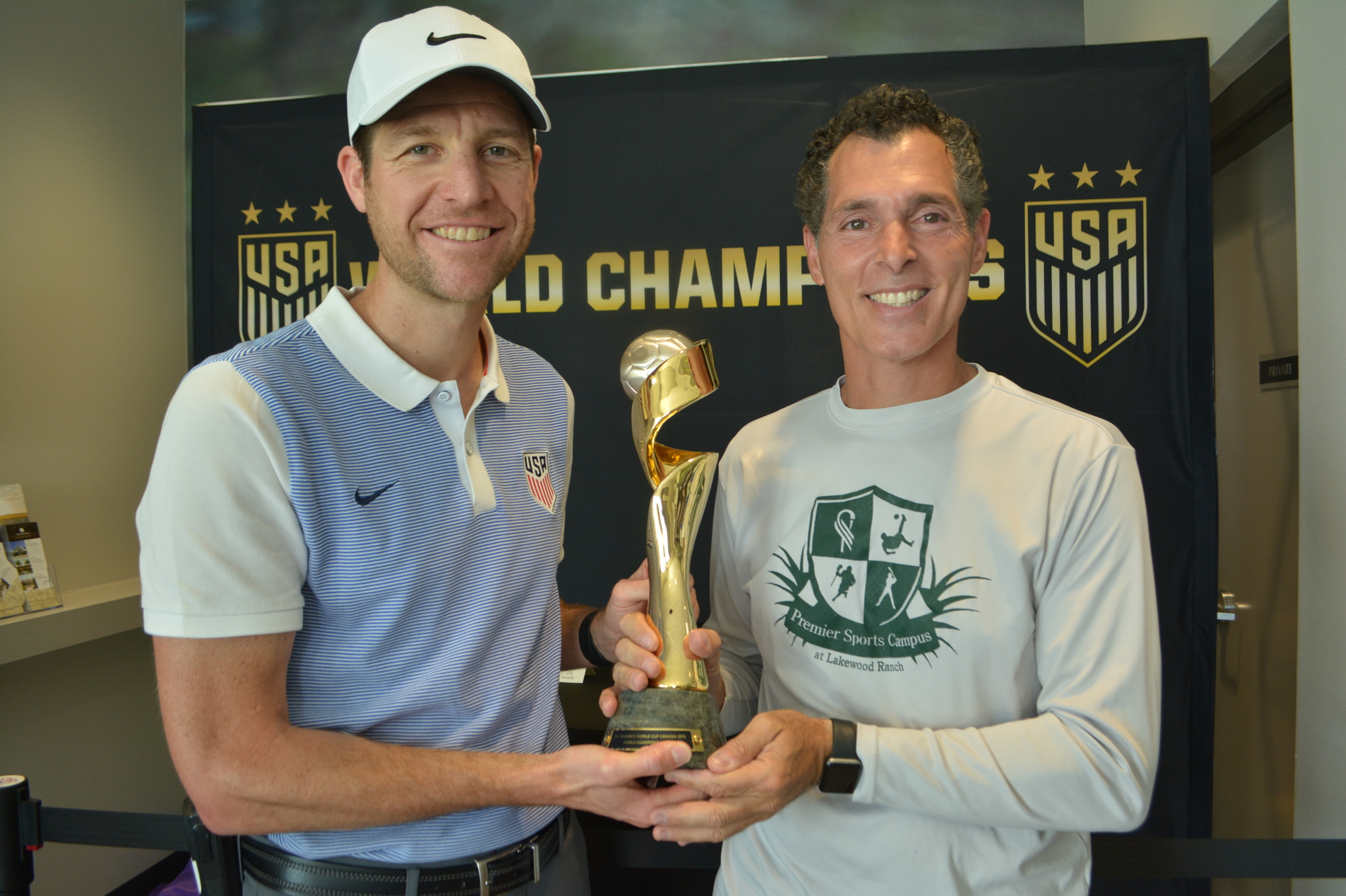 Jared Micklos, the director of Development Academy for the U.S. Soccer Federation, holds the 2015 Women's World Cup trophy with Premier Sports Campus Director Antonio Saviano.