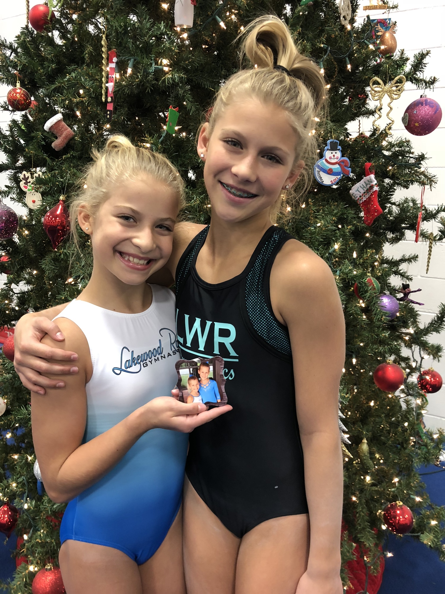 Bri and Taylor Folkers pose with the ornament they donated to Lakewood Ranch Gymnastics six years ago.