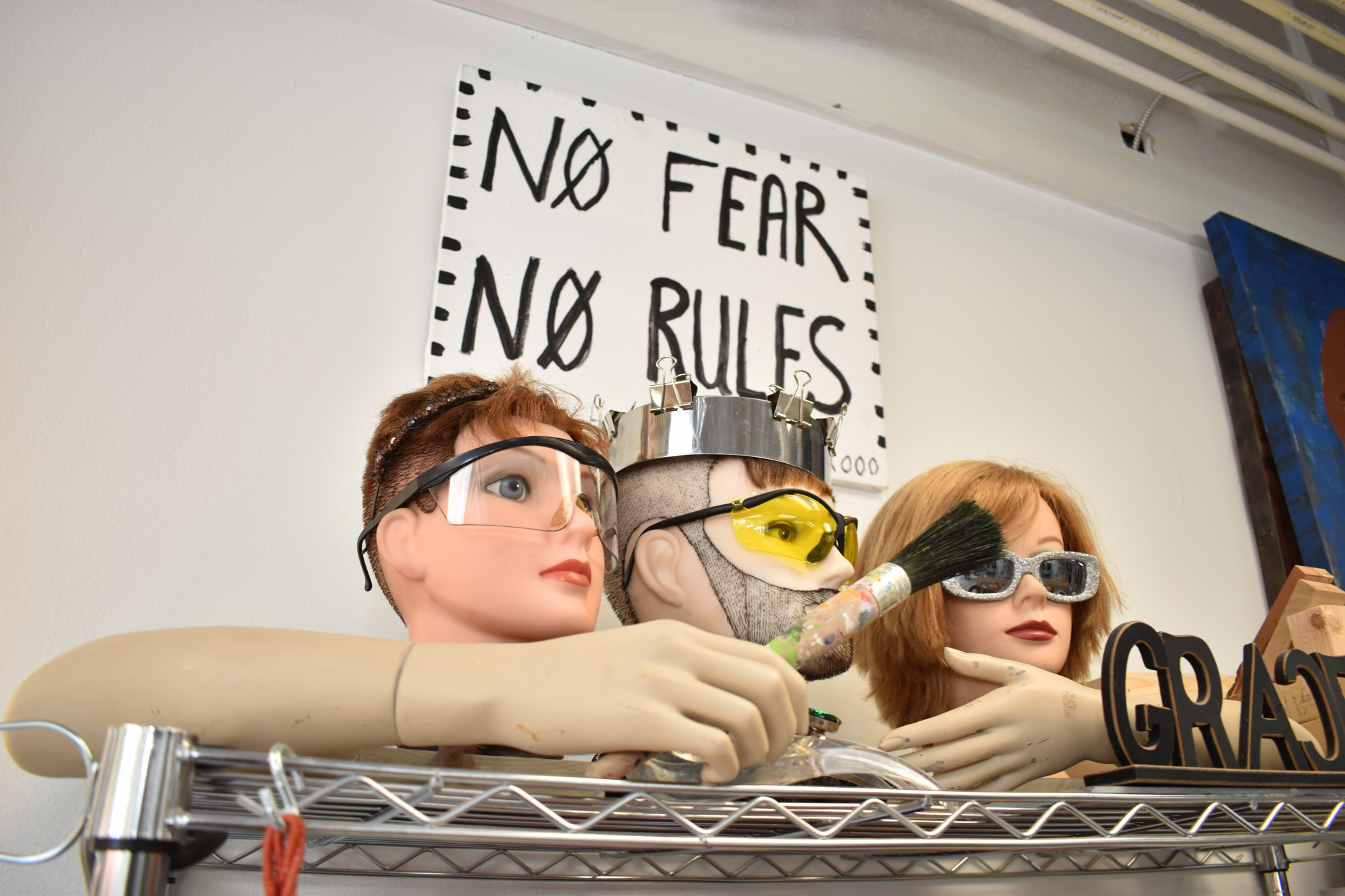 Grace Howl's mantra hangs on the wall behind her mannequin head collection. Photo by Niki Kottmann