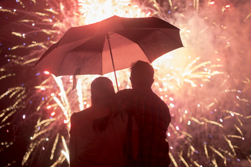 Jackie Smith and Mike Garrett watch the finale of the 2017 Siesta Key fireworks from under an umbrella.