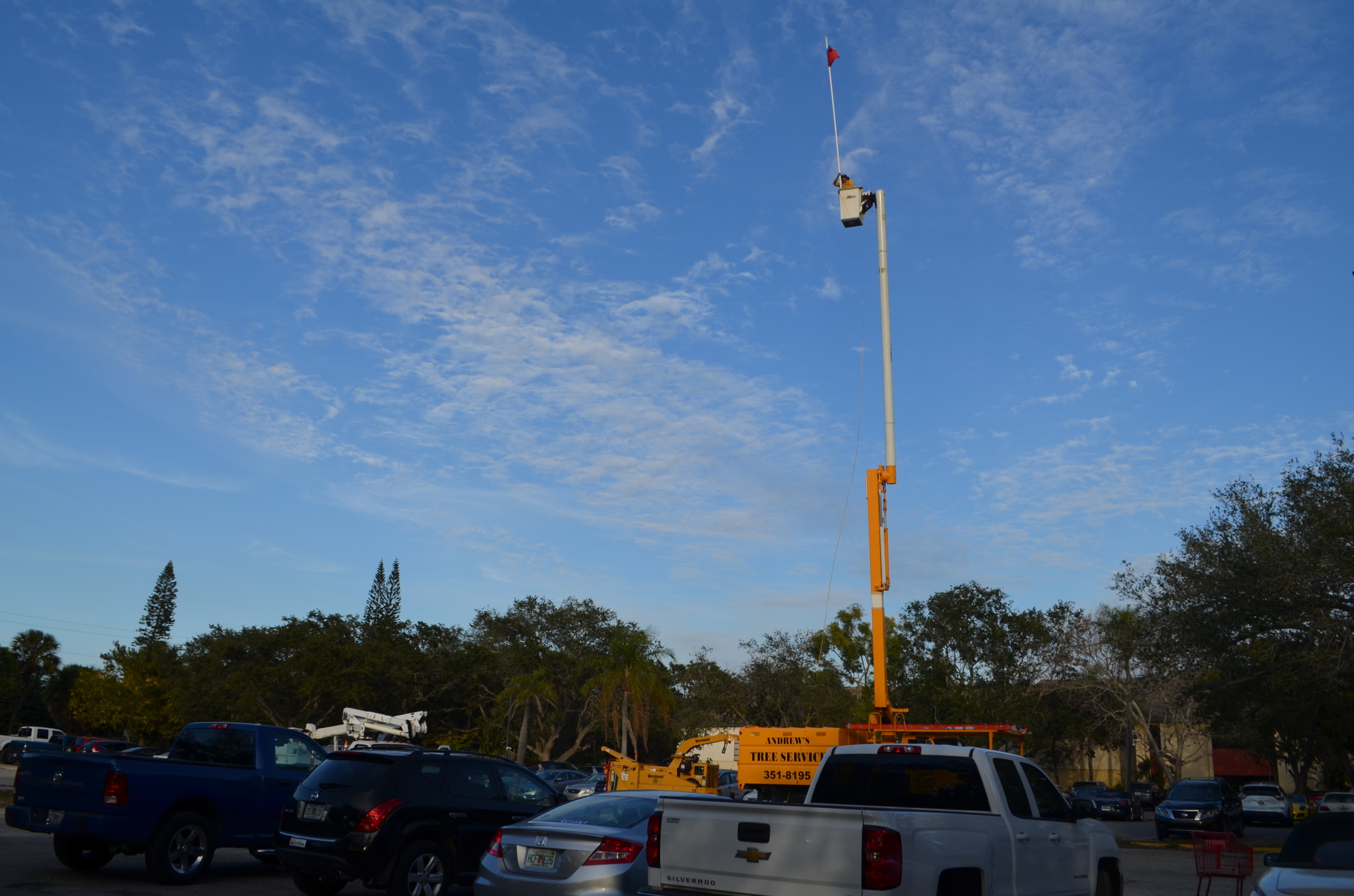 A man in a bucket truck holds a flag 81 feet above the ground to mark the proposed height of a seven-story building in what is currently the Bath and Racquet Club parking lot.