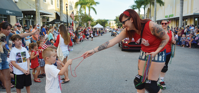 Sarah Bikos of the Bradentucky Bombers Roller Derby team reaches out to Lakewood Ranch's Wayne Comegno, 5, who gets some beads during the 2017 Tribute to Heroes Parade.