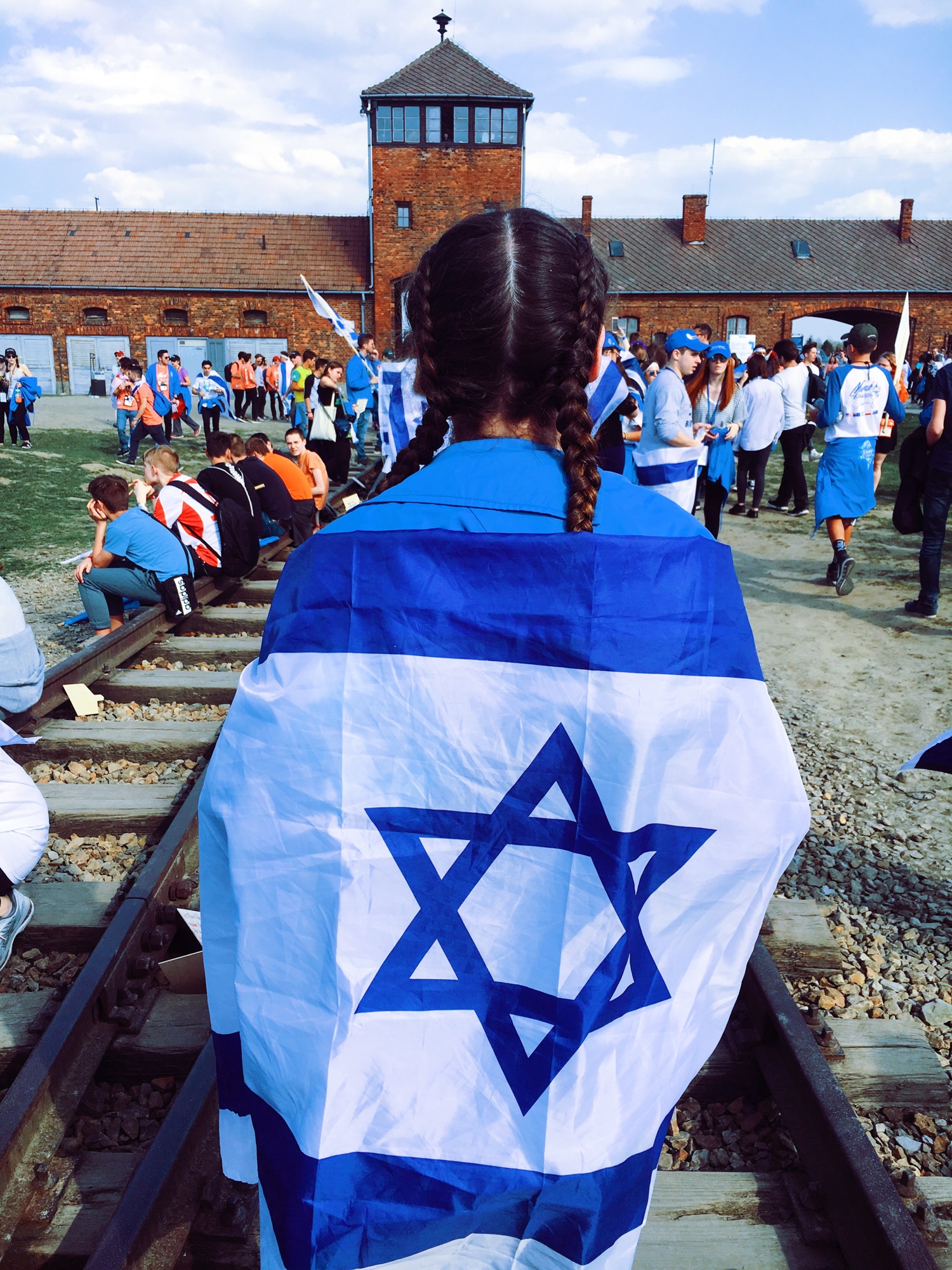 GreyHawk Landing's Abigail Zion is wrapped in an Israeli flag outside the Auschwitz concentration camp in Poland.
