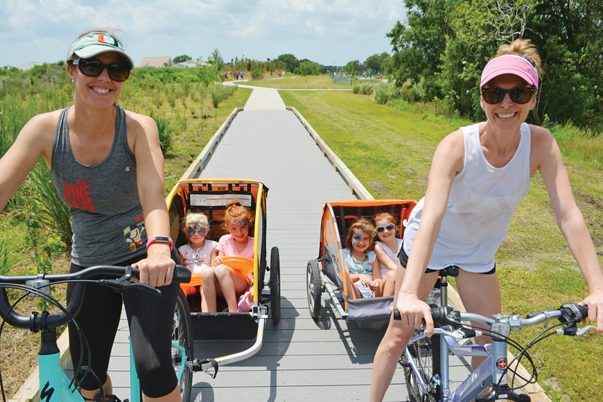 Lakewood Ranch’s Crystal Oliveira and Heritage Harbour’s Katie Trusz pedal their kids, Everly Trusz, 3, Julia Oliveira, 6, Emerson Trusz, 5, and Claire Oliveira, 4, to the April 21 grand opening of Bob Gardner Park. 