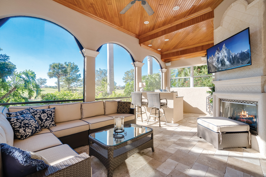 The outdoor living area by the pool features a fireplace, TV and outdoor kitchen.