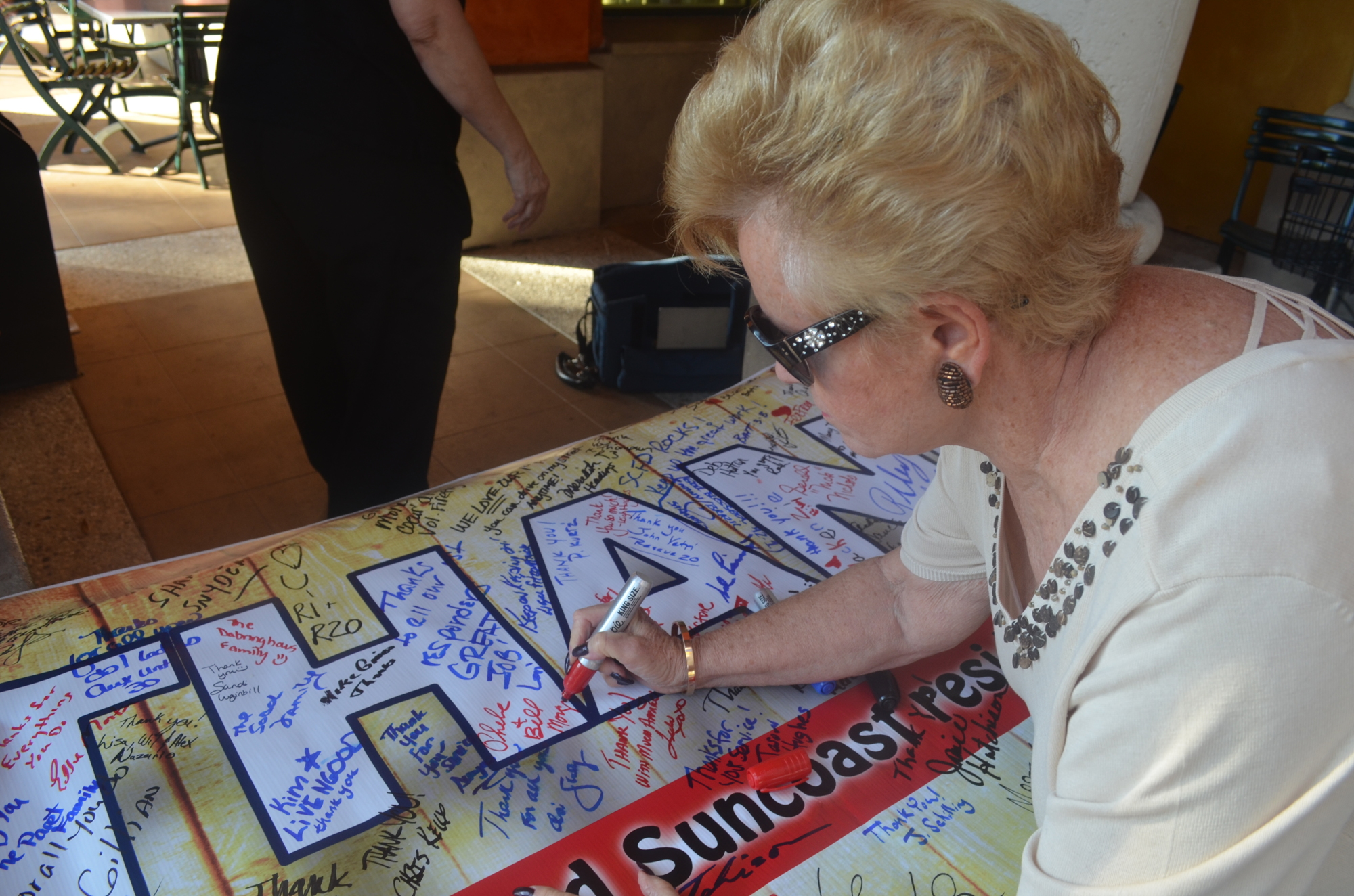 Phebe Morgan signs a banner thanking firefighters and paramedics at Morton's Gourmet Market this morning.