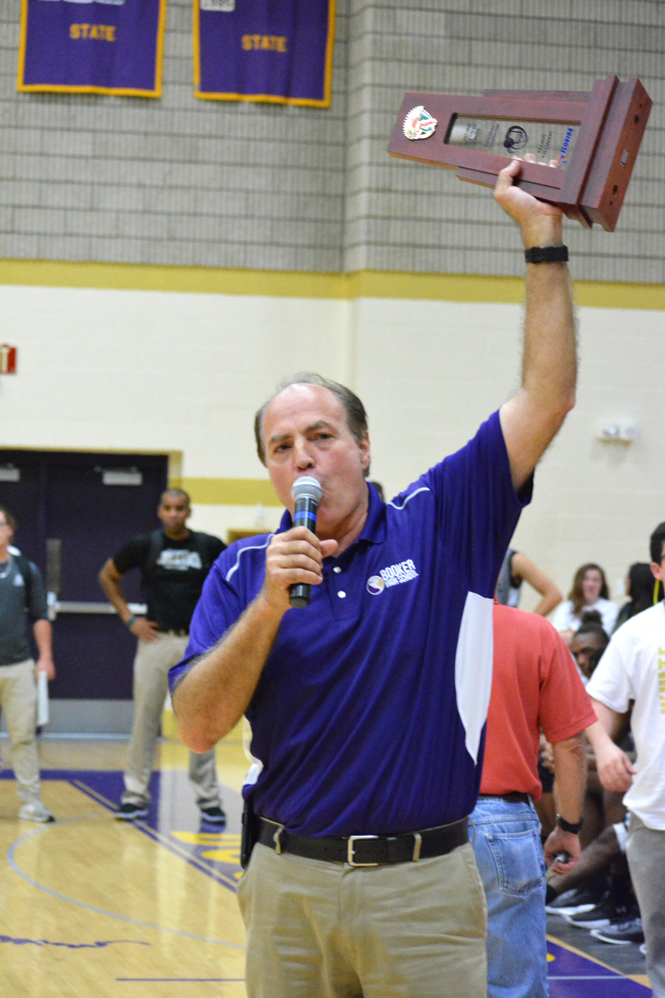 Booker athletic director Phil Helmuth raises the boys basketball team's 2017-2018 regional championship trophy.