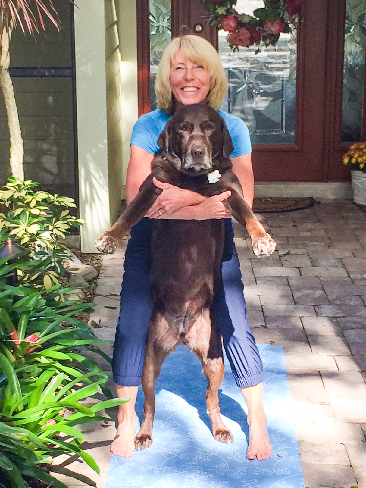 Yoga from the Heart instructor Dianne Ochiltree in chair pose with her and her Labrador, Sally.