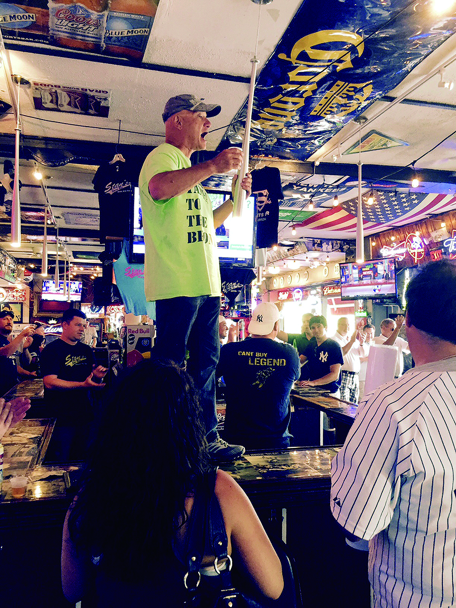 Richard Albero stands on the bar at Stan’s after completing his trek, giving a toast to his nephew, Gary.