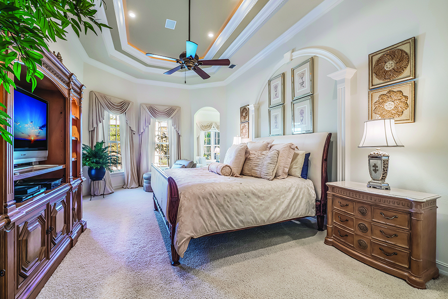 Another coffered ceiling and custom moldings add character to the luxurious bedroom.