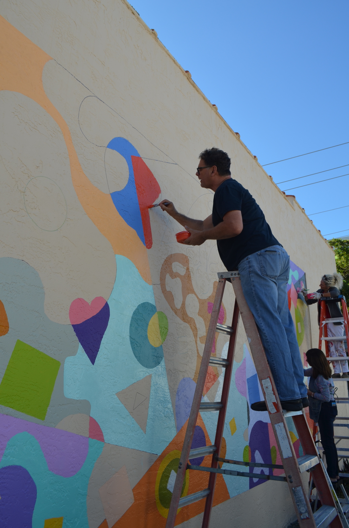Artist Jeff Hostetler fills in a portion of a new Rosemary District mural.