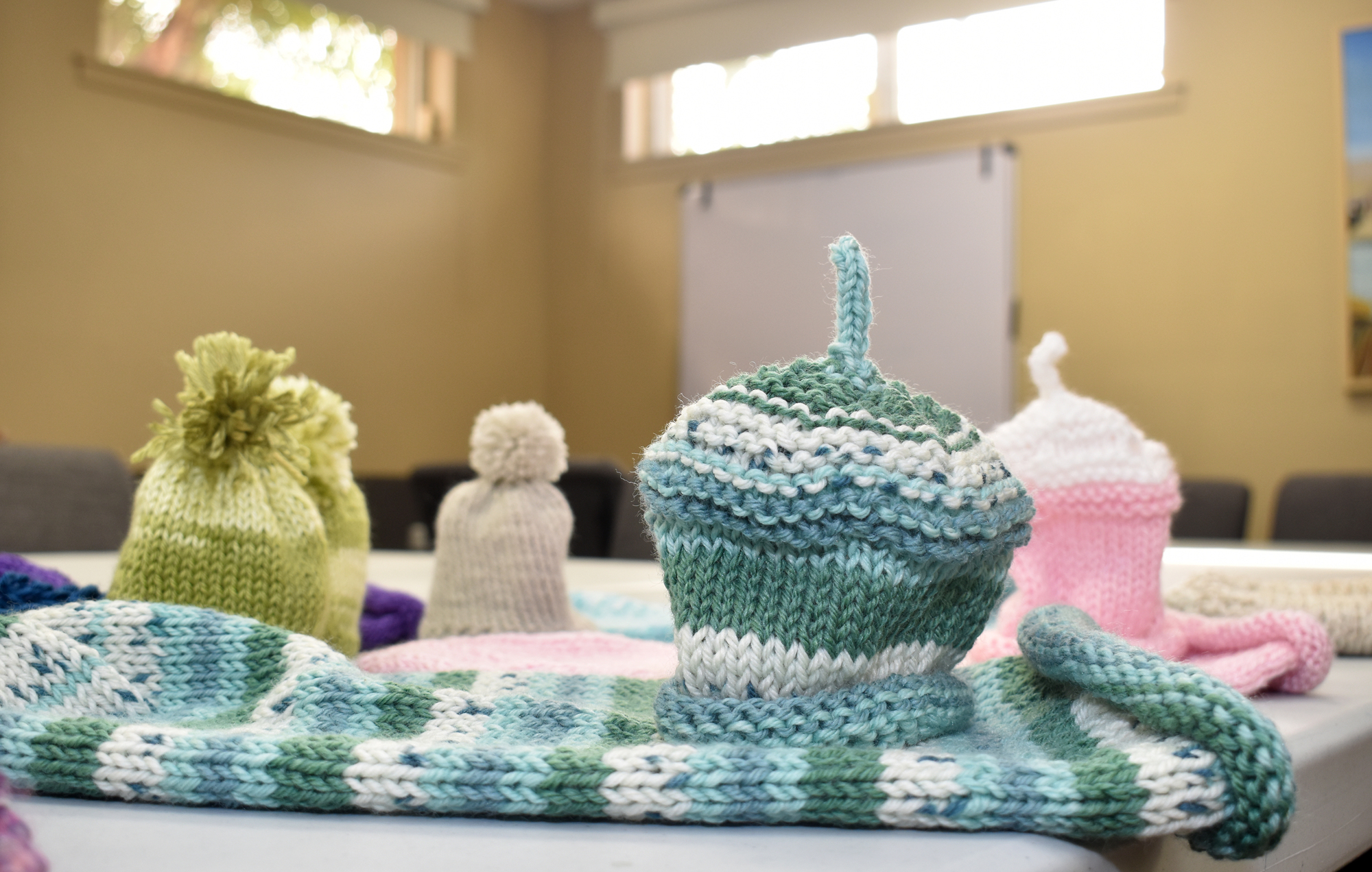 This year, the group is making something new in addition to the shawls and scarves. Swaddle Sacks are being knitted with leftover yarn to create comfort for newborns.