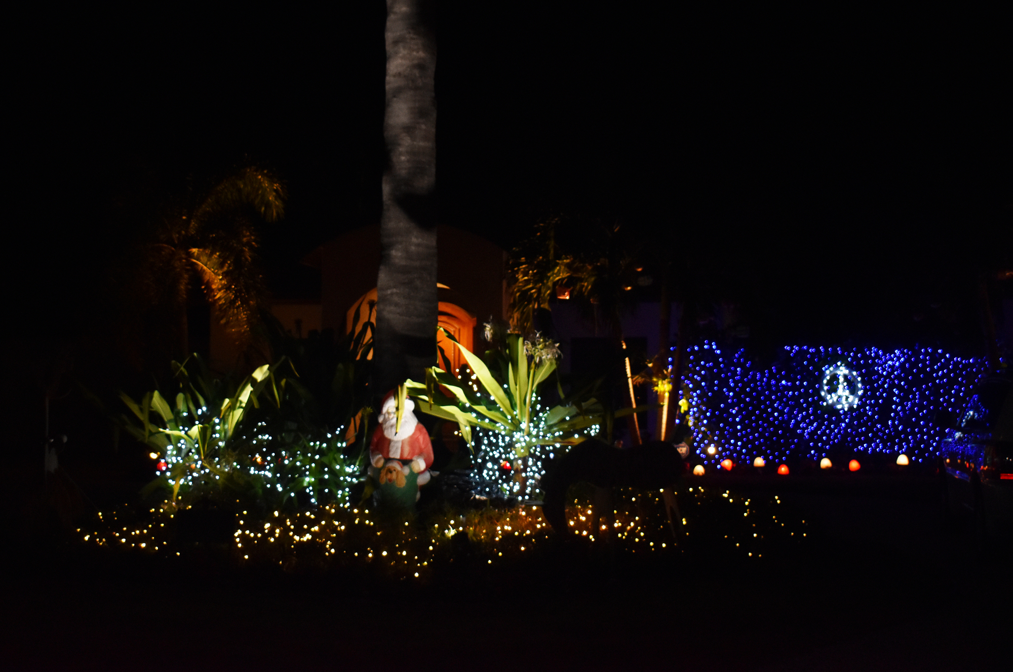 An Emerald Harbor home features Santa sitting in a bush with a peace sign behind him.