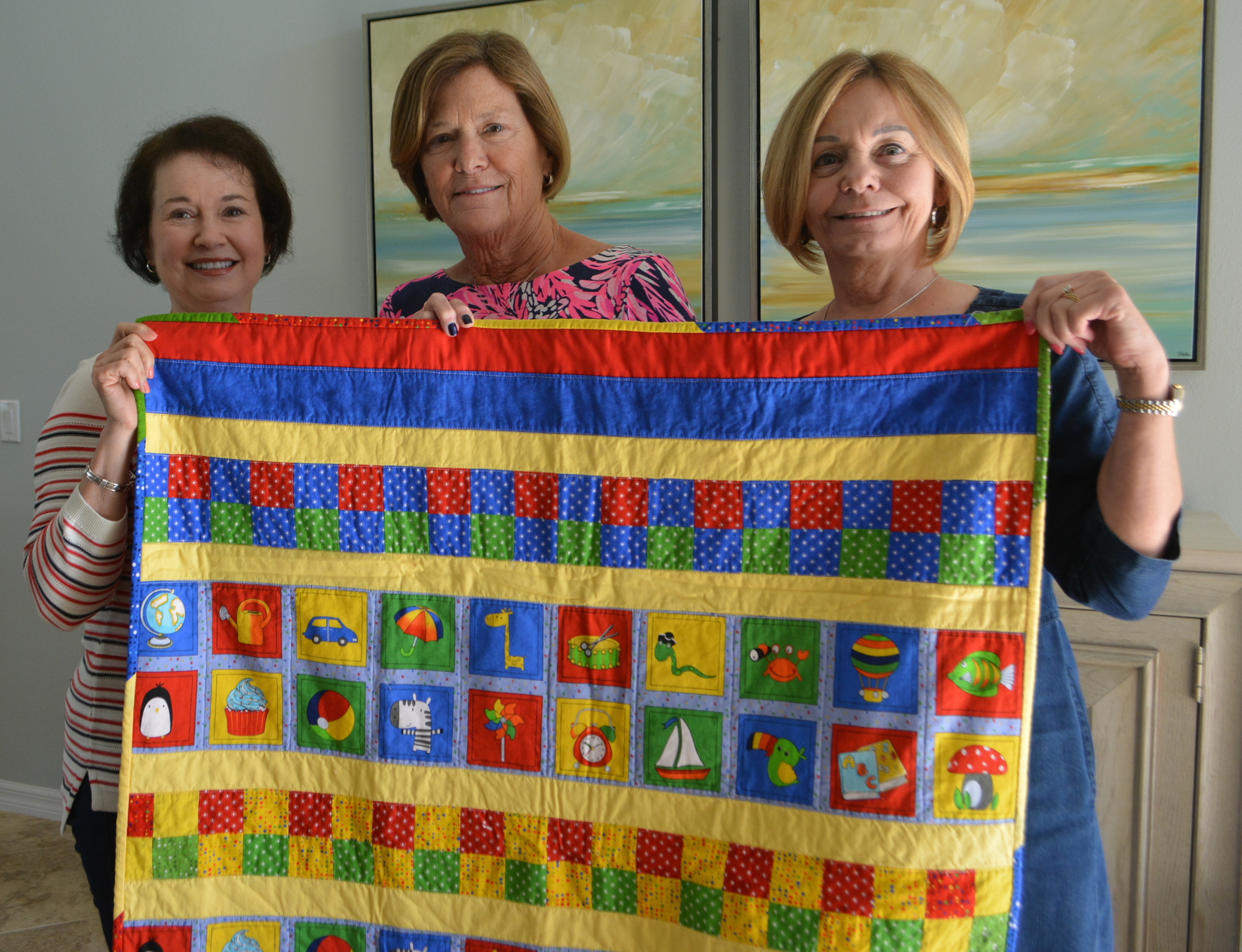 Pam Szabo, Linda Stone and Diane Laybourn show off a blanket headed to a charity.
