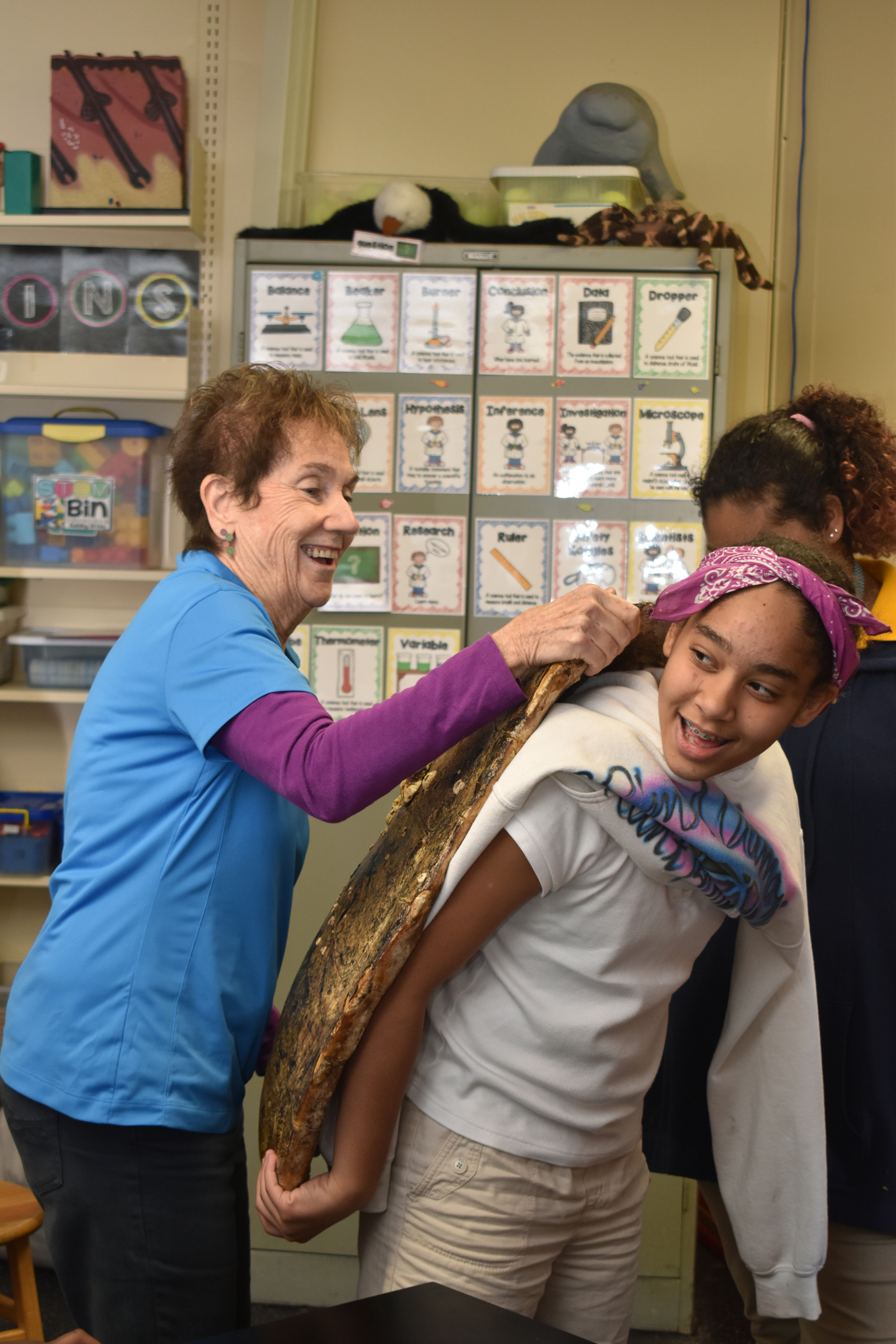 Ann Tannen helps a fifth grade student try on a carapace.