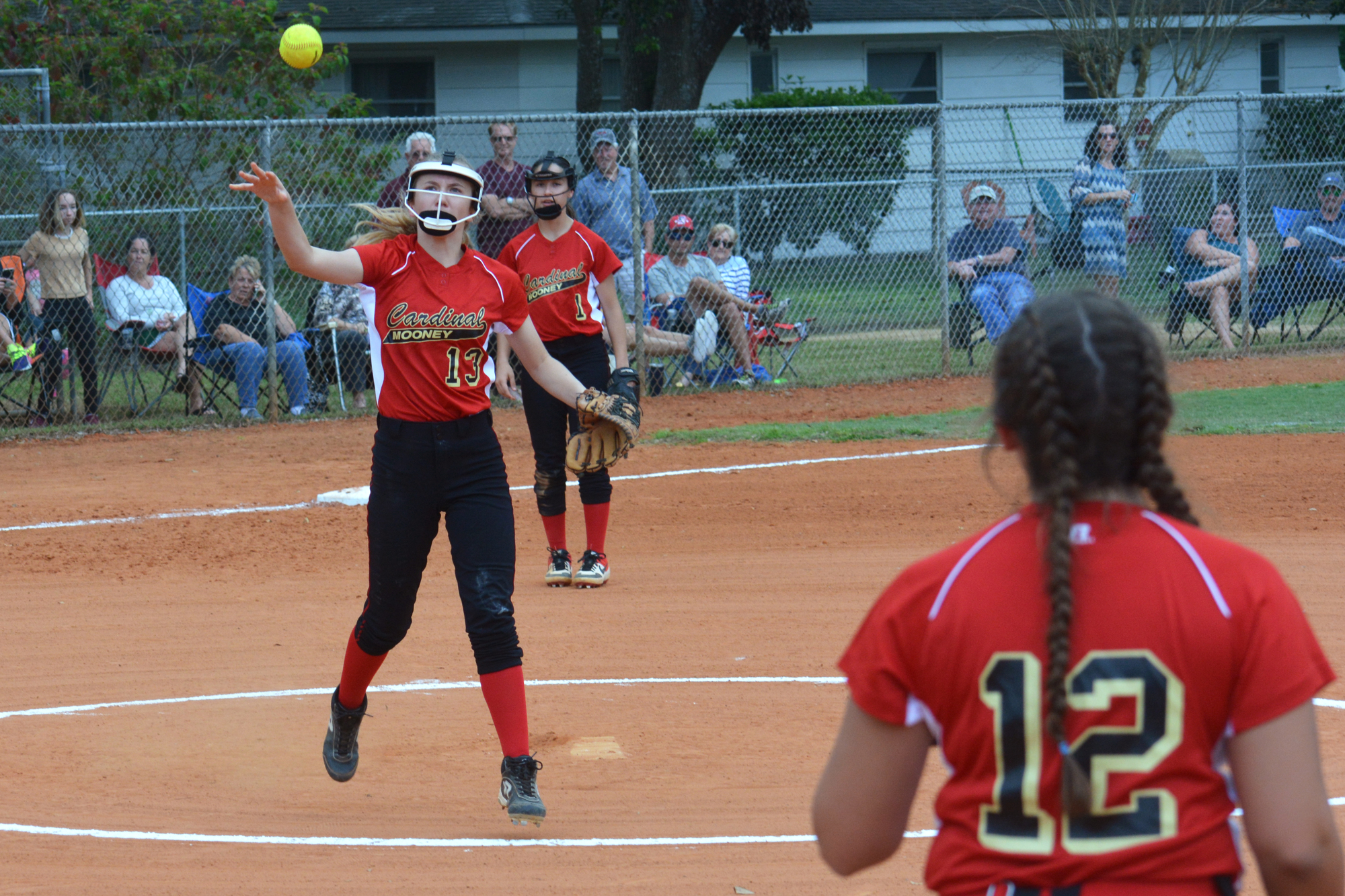 Freshman pitcher Emma Plumley tosses a ball to junior first baseman Gianna Newsome (12).
