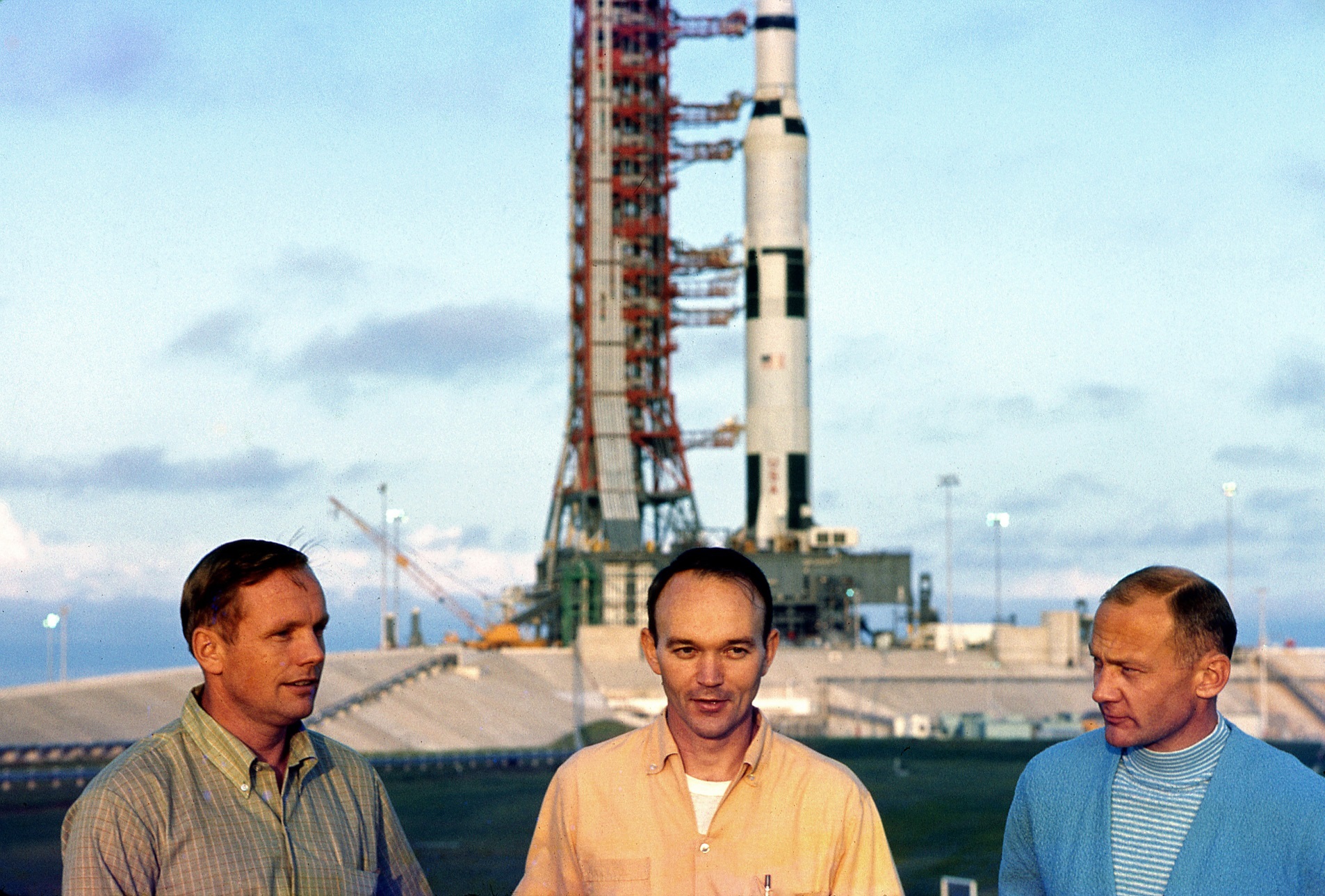 Neil Armstrong, Mike Collins and Buzz Aldrin talking with reporters in front of their Saturn V after it was rolled to the launch pad on May 20, 1969.