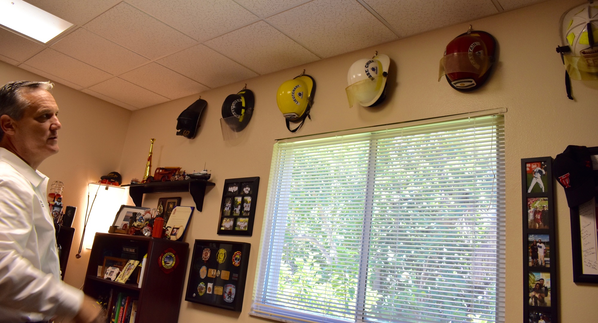Dezzi examines his collection of fire helmets, which show, in part, the progression of his career.