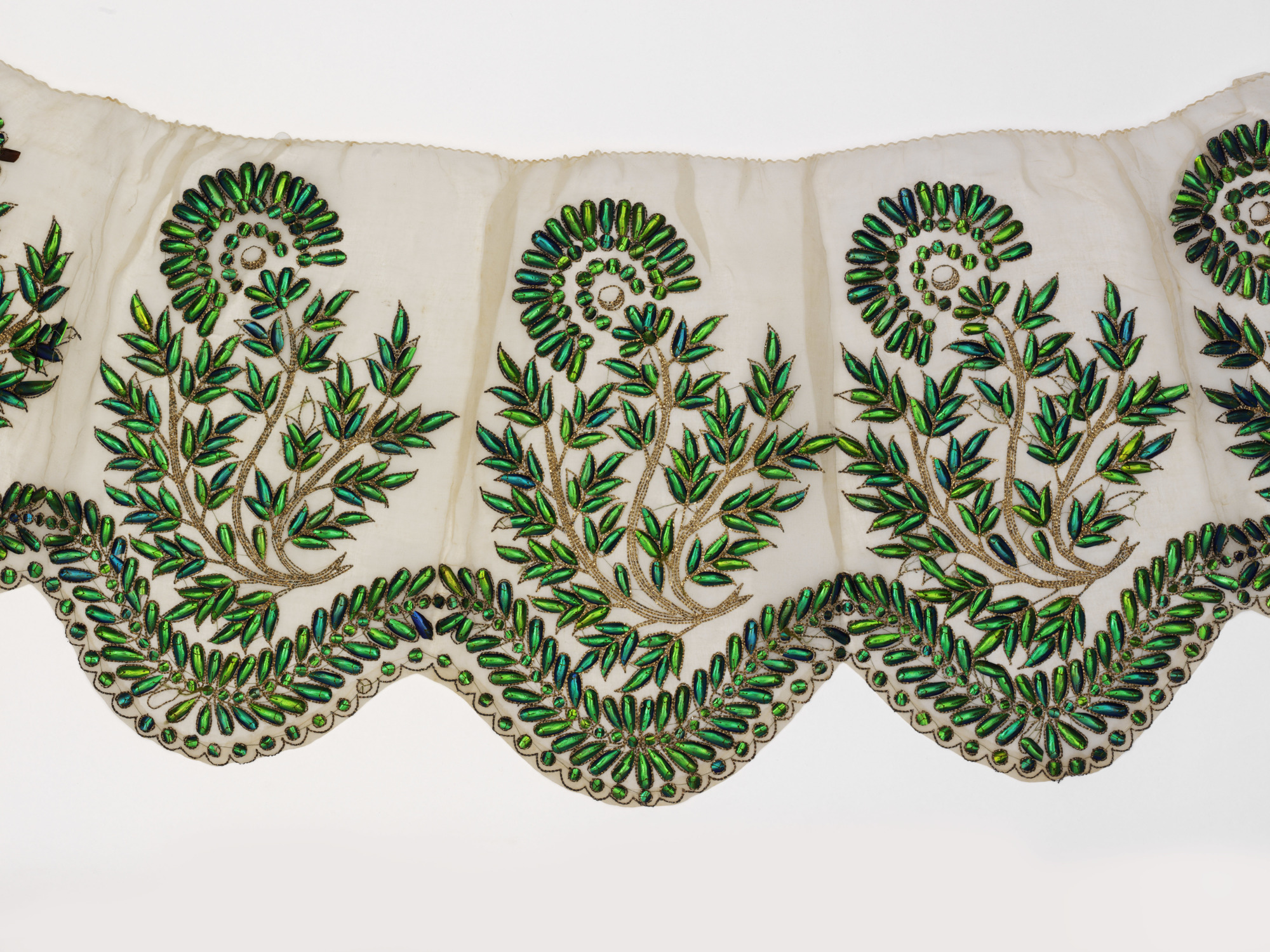 This 19th century dress border is made of cotton embroidered with beetle-wing cases, couched with gilt-silver wire; given by Mary Gordon — Photos courtesy Victoria and Albert Museum, London
