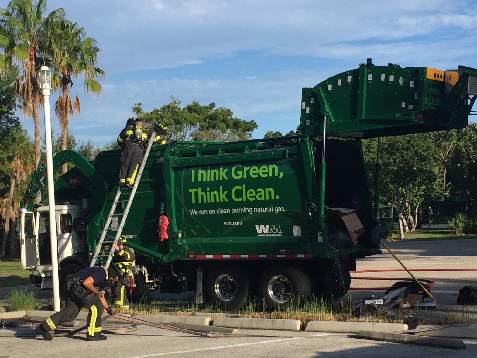 Firefighters used ladders to access the hopper of the Waste Management truck.
