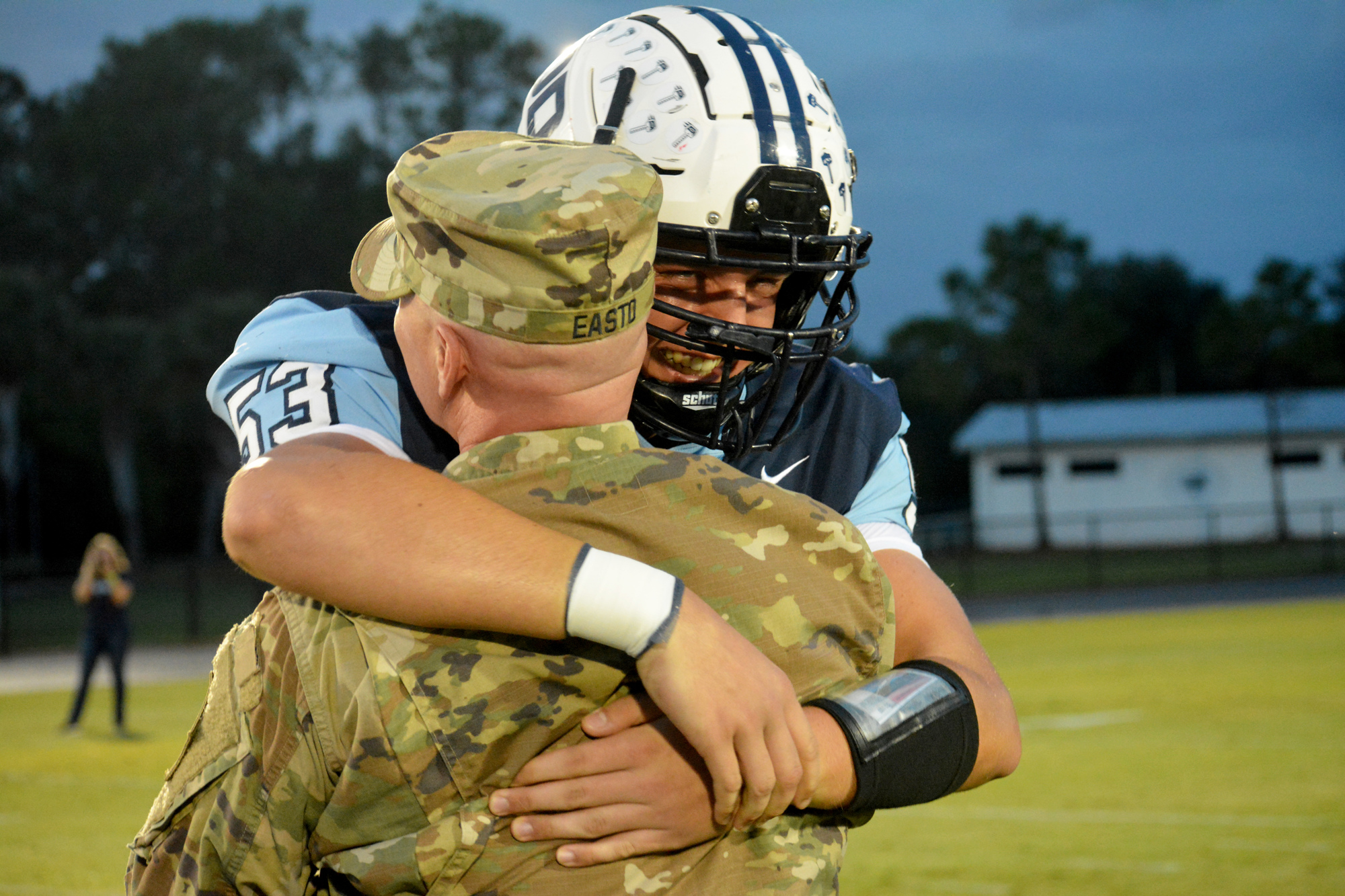 Out-of-Door Academy senior JJ Easto hugs his father, Capt. Josh Easto, after a surprise homecoming during a football game. Photo by Ryan Kohn.