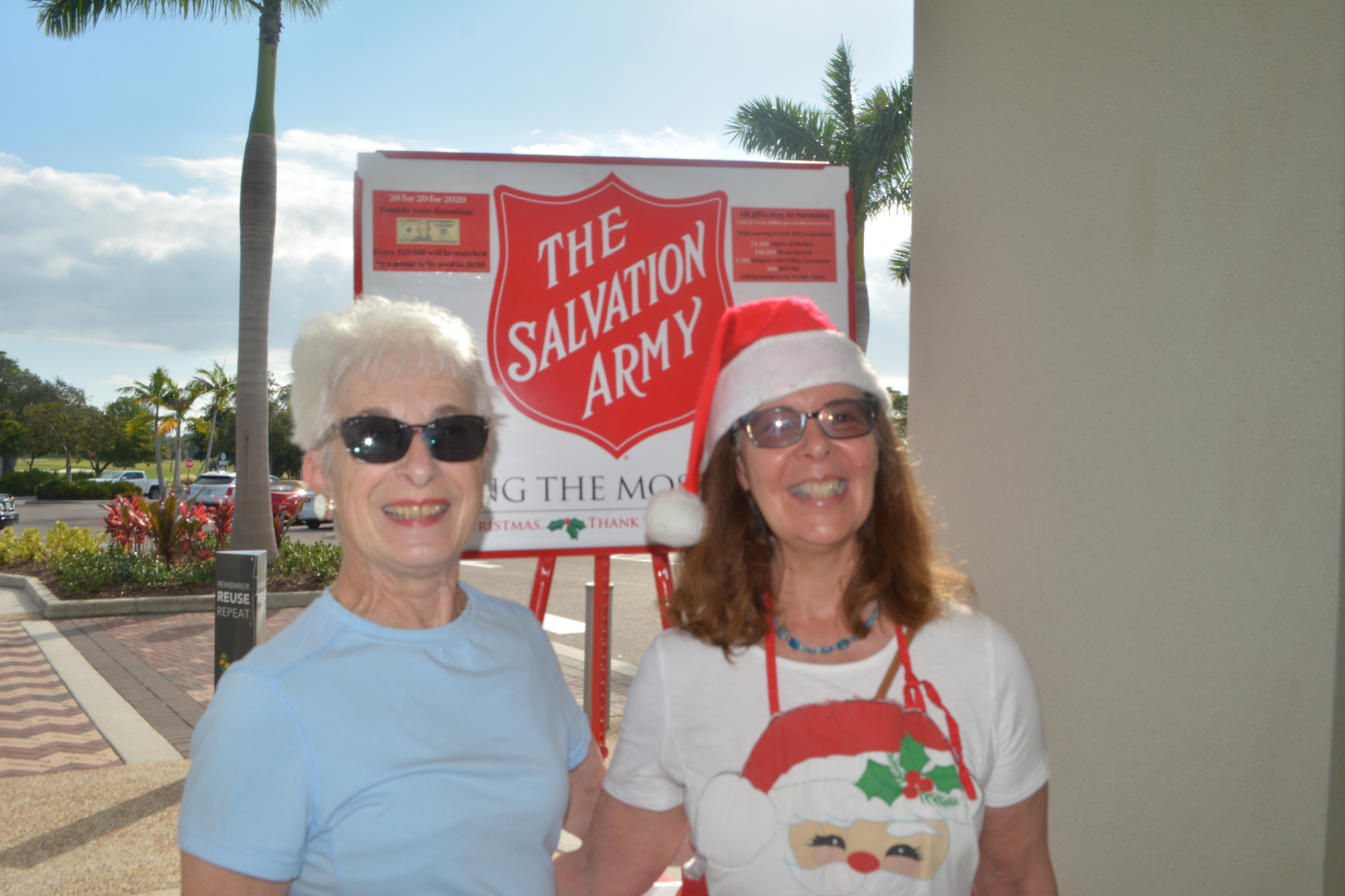 Beth Fusco and Pat Bentley stand by the Salvation Army donations sign after Bentley dropped cash in the kettle.