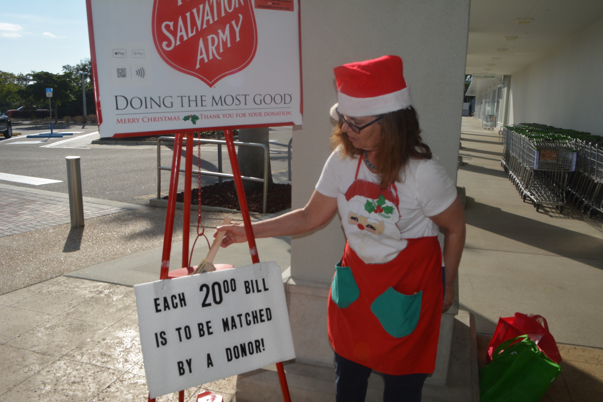 Beth Fusco tamps some of her own cash into the kettle while working a shift as a volunteer bell-ringer.