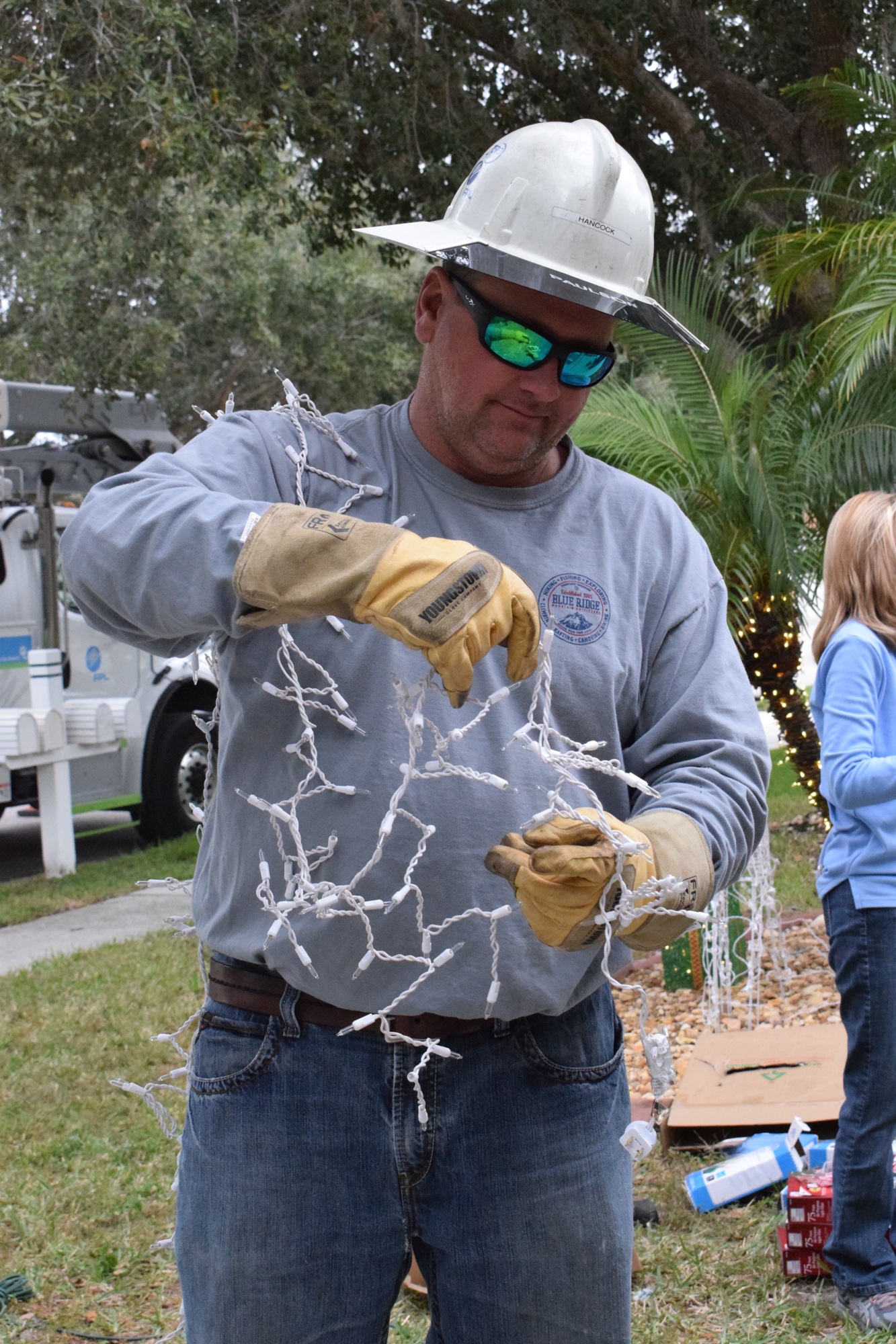 Jeff Hancock, a lineman for Florida Power and Light and a Navy veteran, untangles lights to put on Chris Scott's home. Scott is also a Navy veteran. 