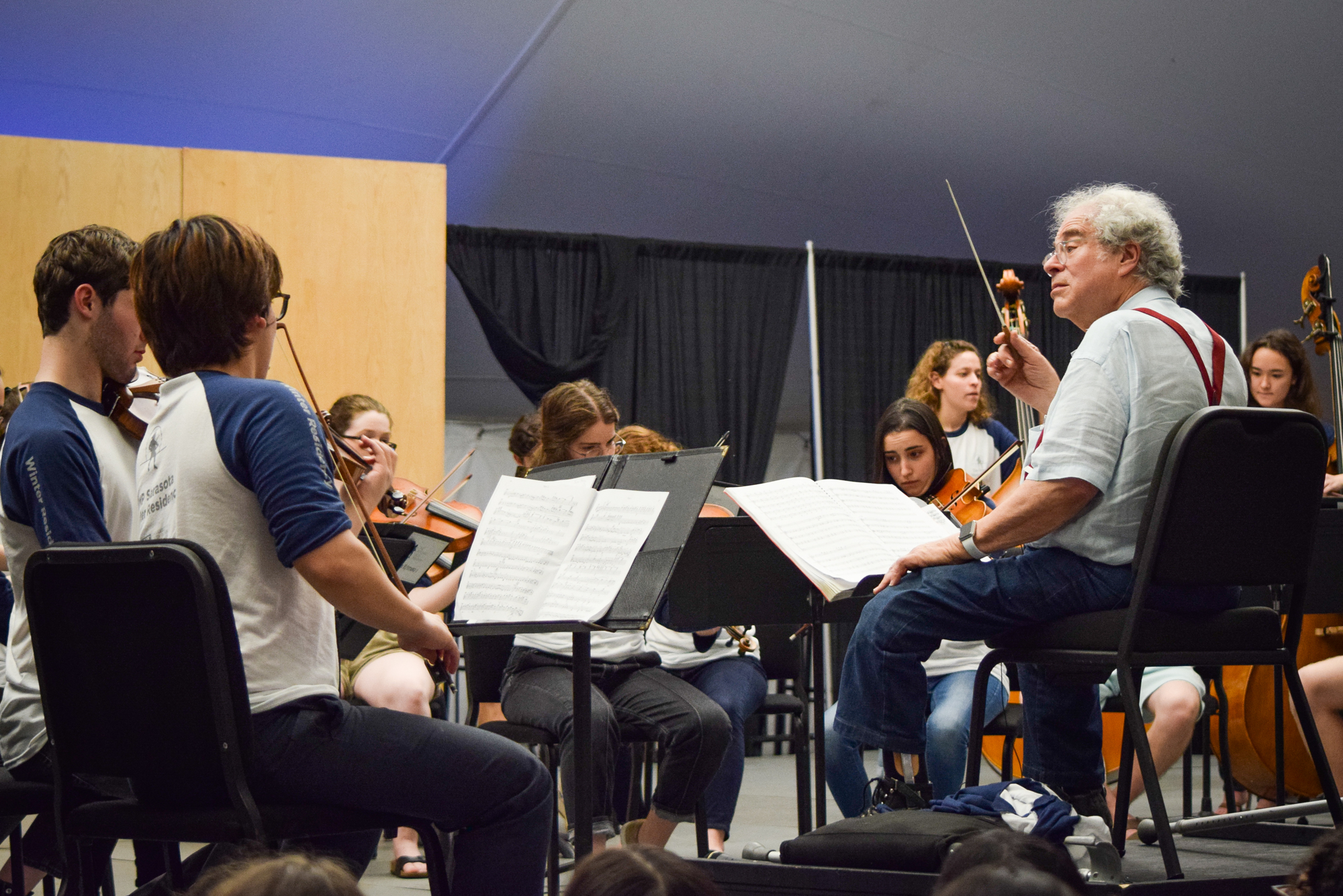 The audience can see and hear the rehearsal process  as Itzhak Perlman leads a start-and-stop rehearsal.
