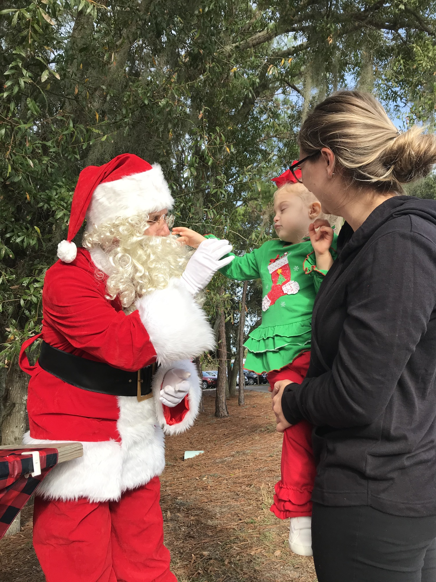Longboat Key Fire Chief Paul Dezzi, dressed as Santa Claus, greets Lili Michel while Lili's mother, Katrina, holds her on Dec. 21 at Nathan Benderson Park.