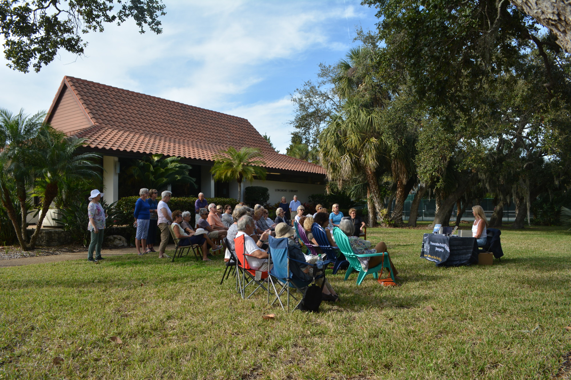 Attendees listen to Sally Fernandez as she speaks at a book signing Sunday on the lawn of Longboat Library.