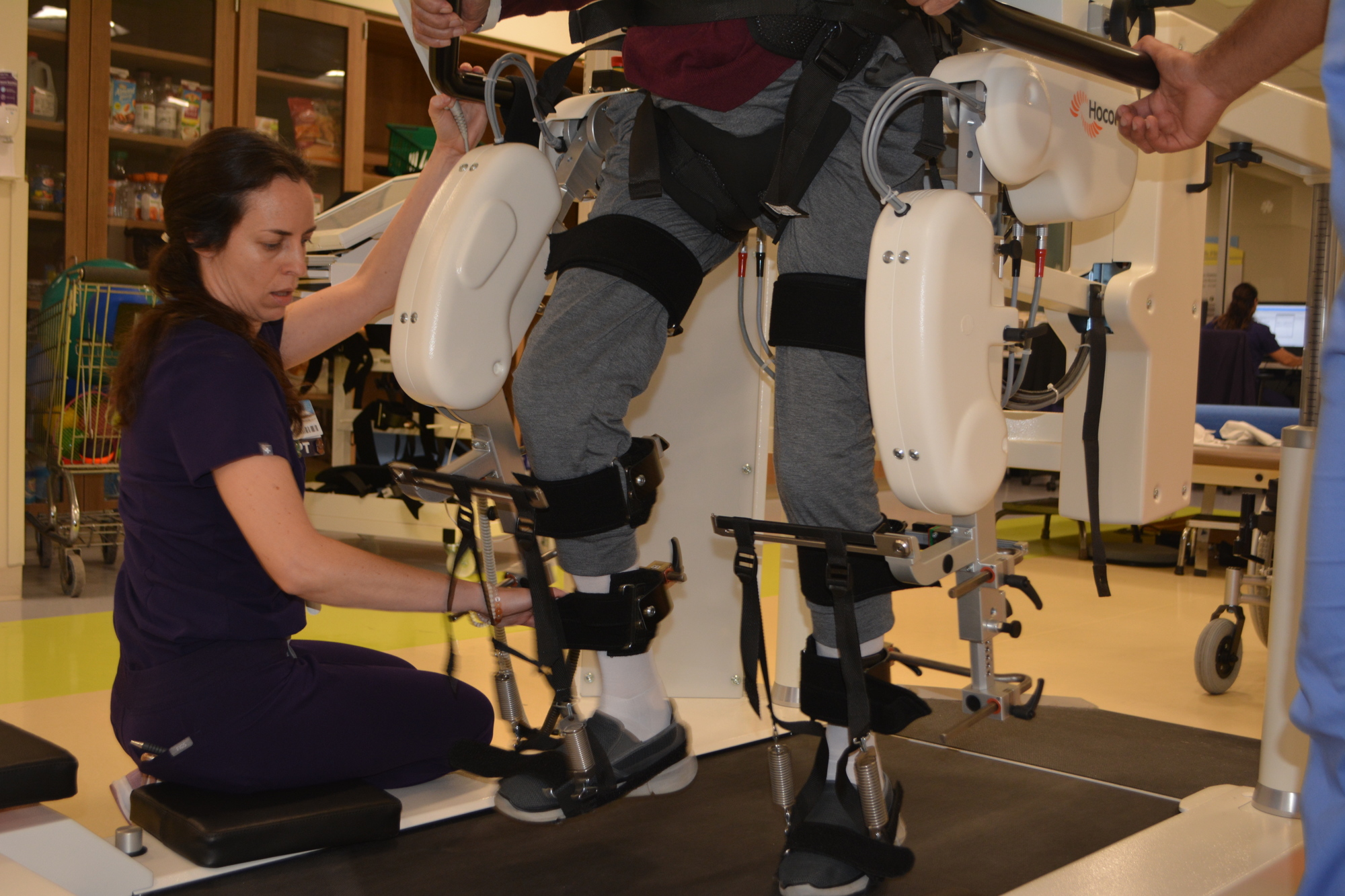 Physical therapist Dr. Julia Figueroa (kneeling) watches stroke patient Ronald Serres walk using the Hocoma Lokomat. Figureoa can adjust the weight distribution on Serres' body based on how he's responding.