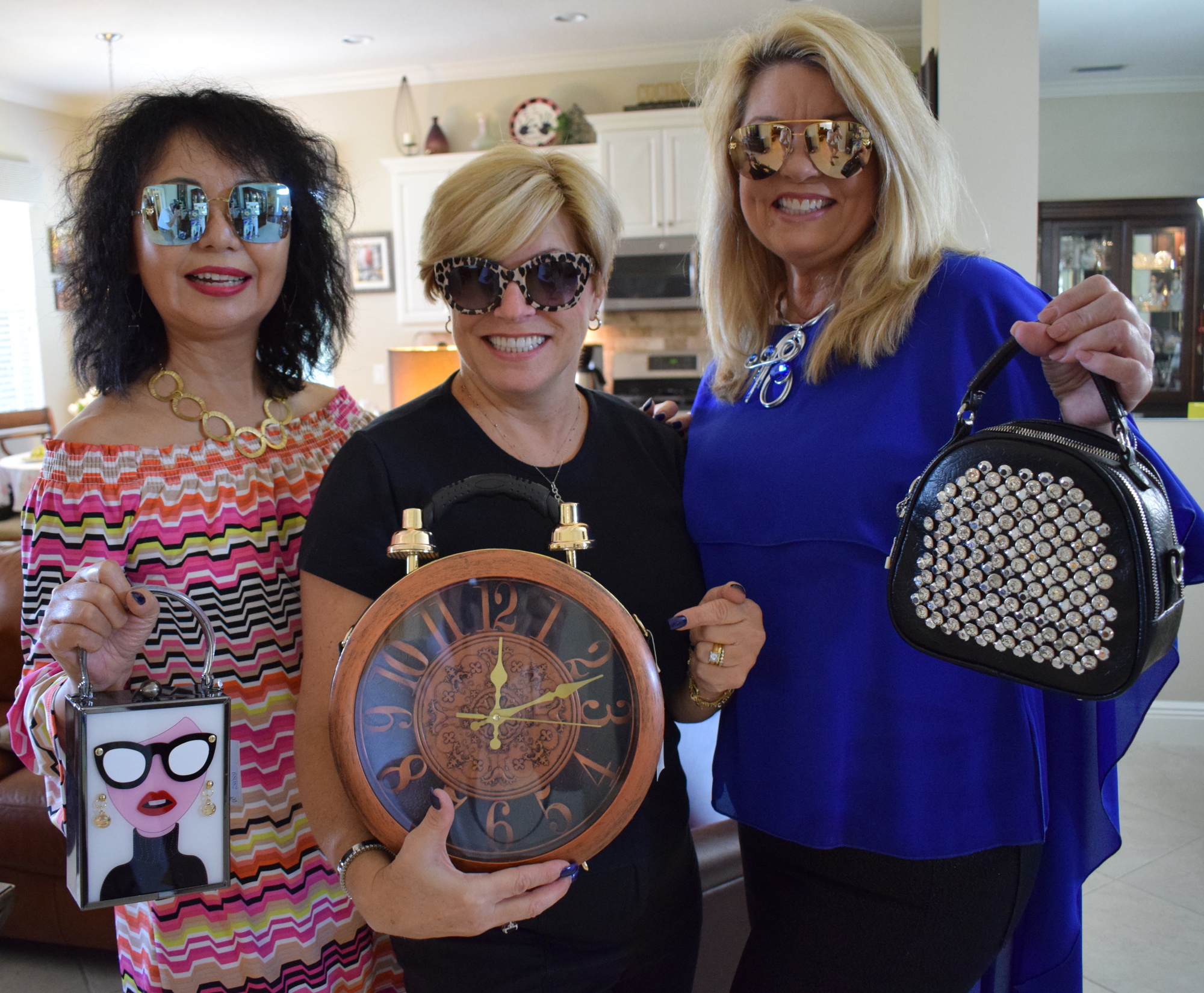 Sisterhood for Good's Kathy Yu, Angela Massaro-Fain and Peggy Kronus show off handbags that will be featured during the event.