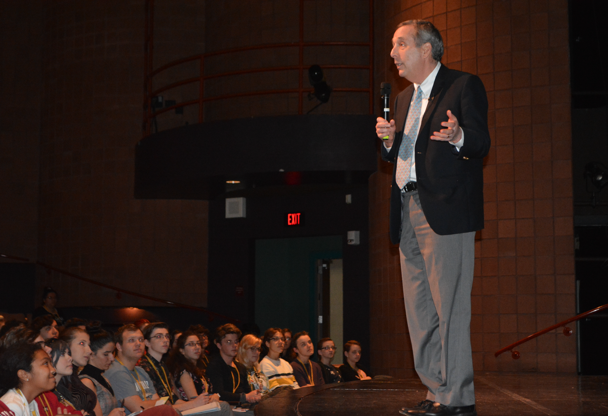 Harvard University president Lawrence Bacow (standing) speaks to students Wednesday afternoon at Booker High School.